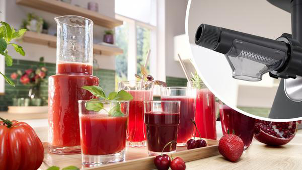 Eine Küchenmaschine, mit Saft und Gläsern mit Saft auf dem Tisch.