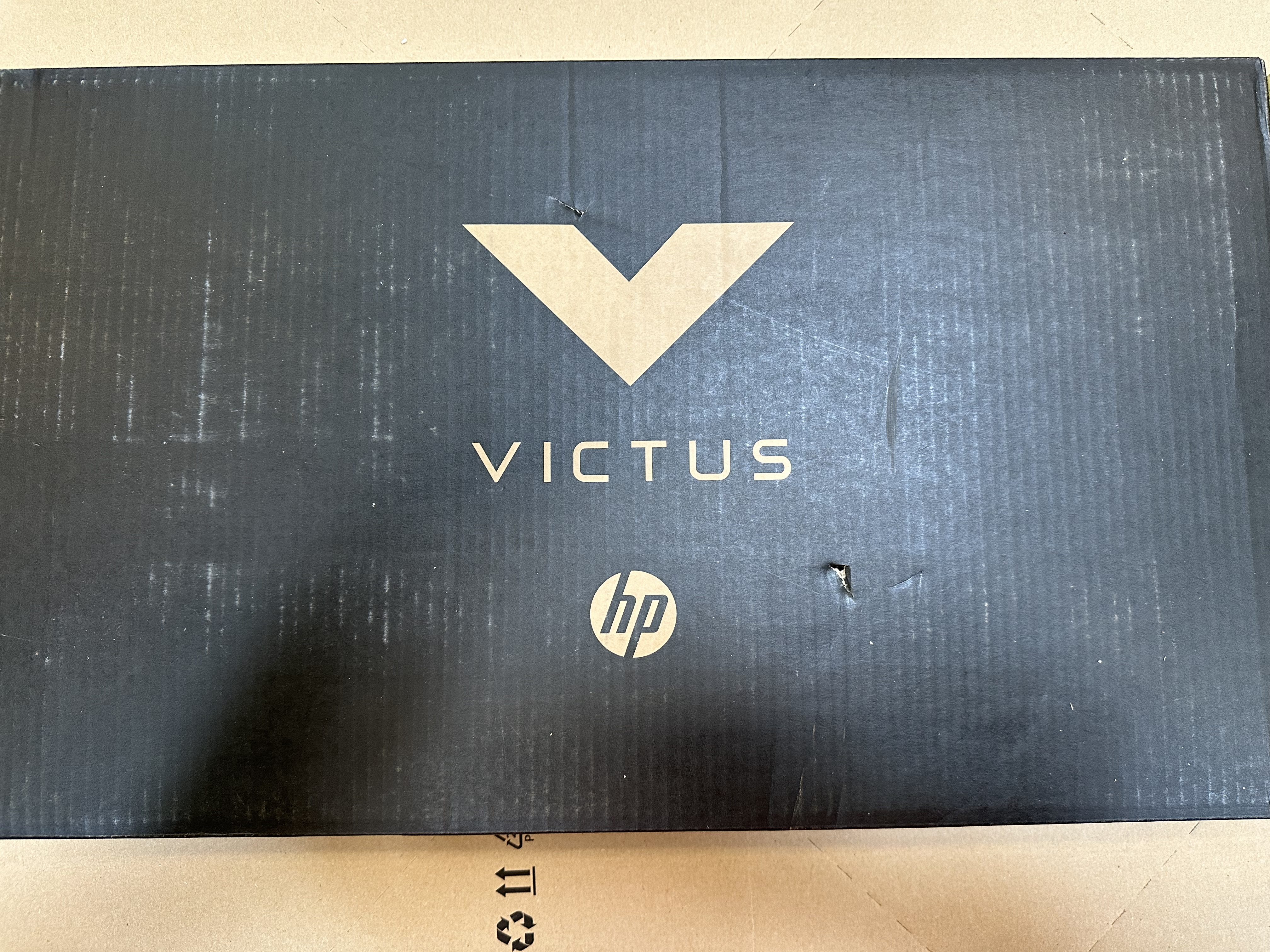 Czarne pudełko od laptopa z logo V oraz logo VICTUS i HP.