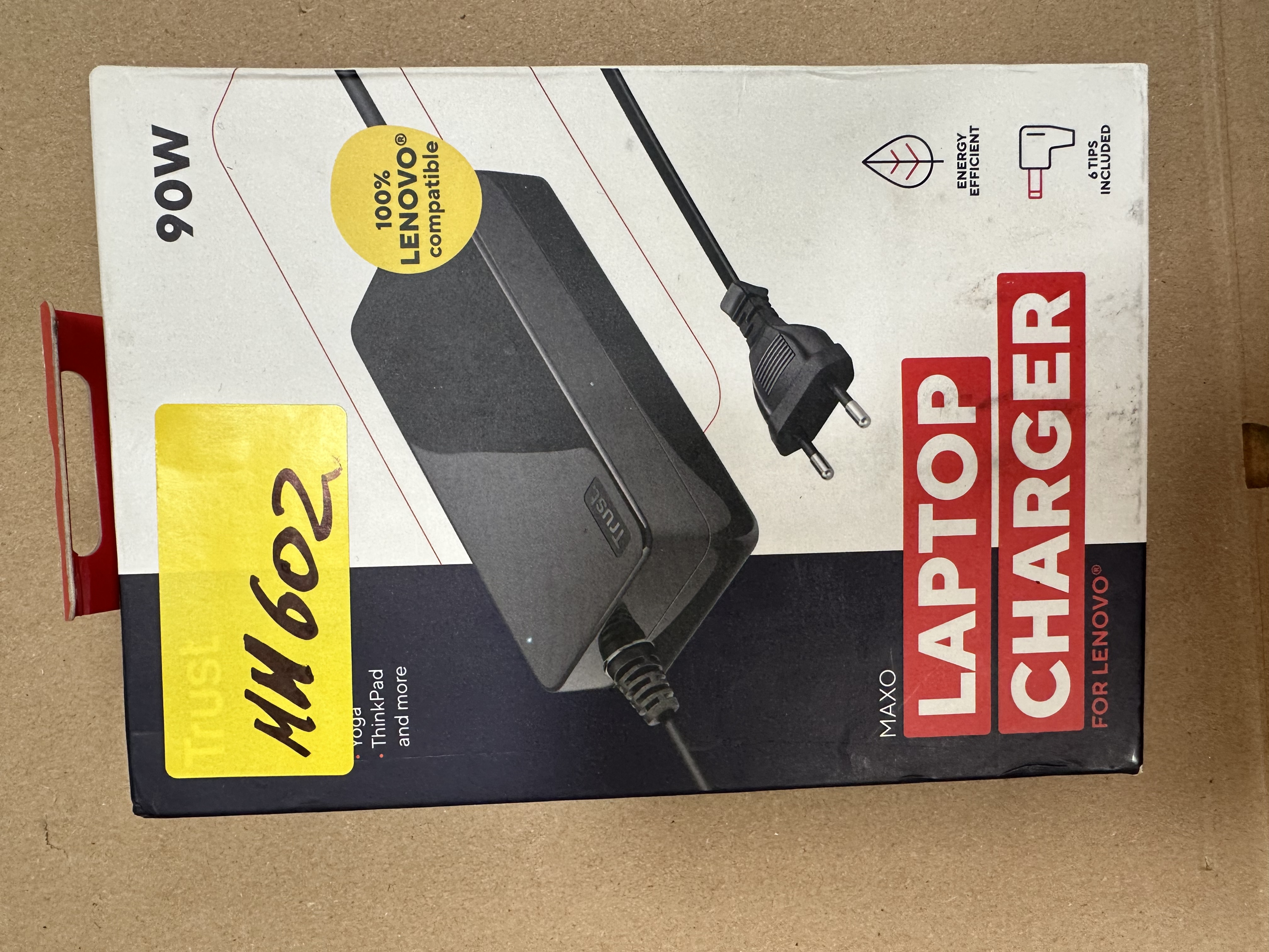 Pudełko ładowarki do laptopa, kompatybilnej z Lenovo. Ma wtyczkę i tekst: Laptop Charger, Maxo, Trust i 90W.