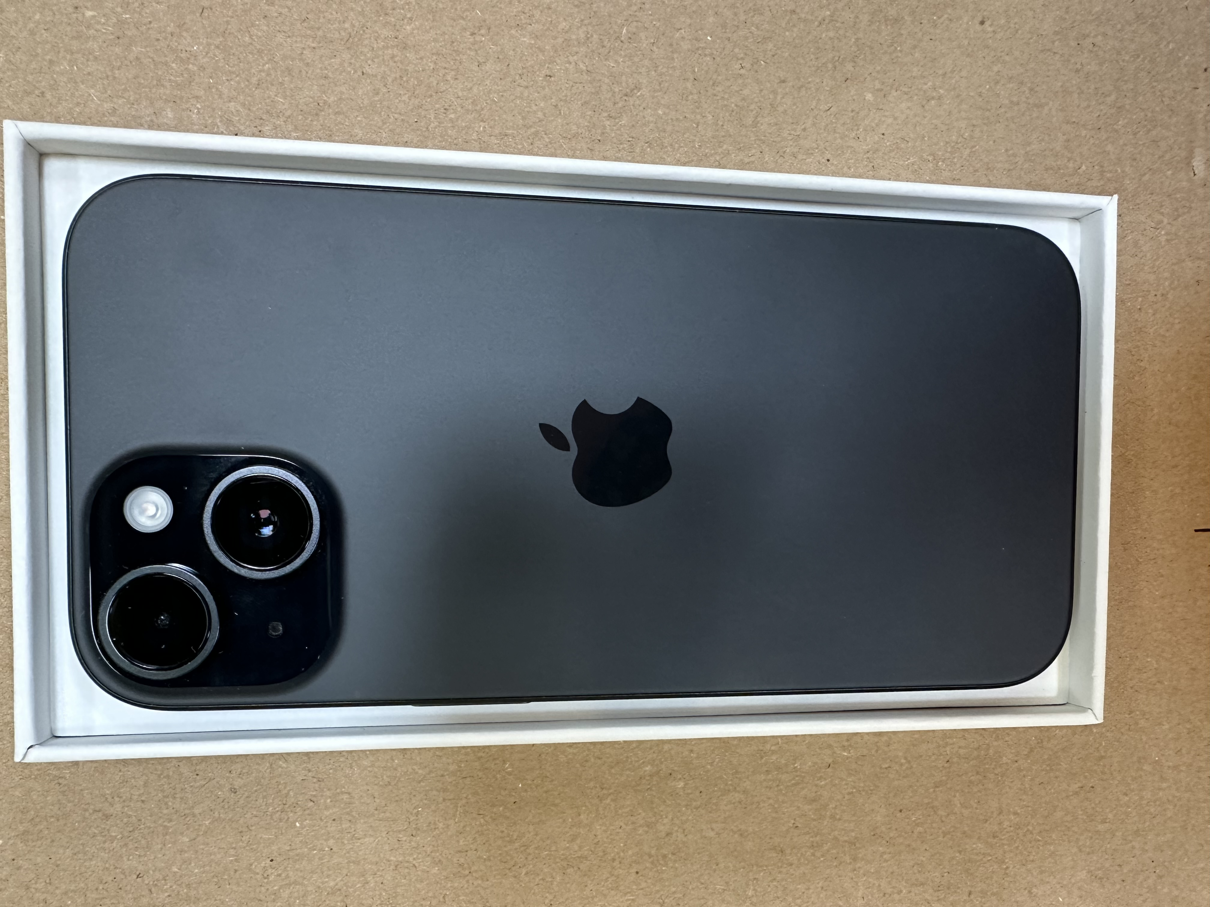 Ciemnoszare iPhone w białym pudełku, tył z dwoma aparatami i logo Apple.