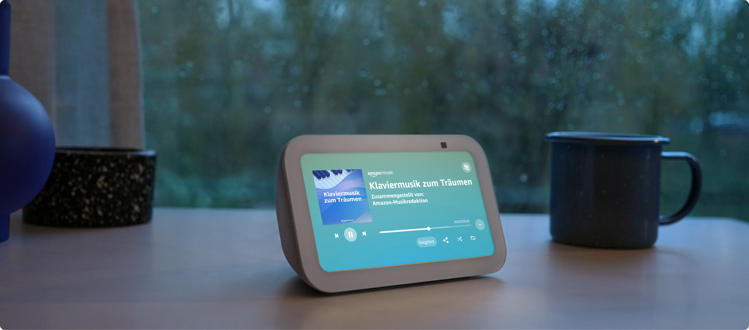 Smart-Display mit Bildschirm, der eine Musikoberfläche neben einer Kaffeetasse zeigt.