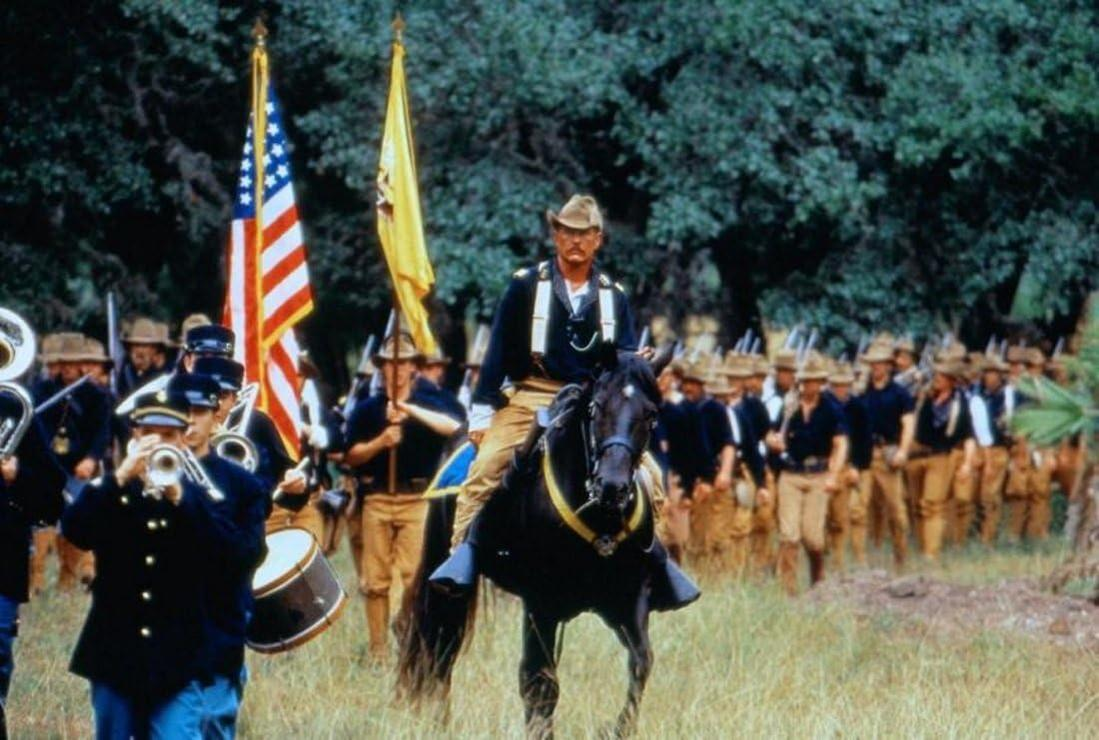 Soldaten in blauen Uniformen marschieren. Ein Mann auf einem schwarzen Pferd führt, Flaggen im Hintergrund.