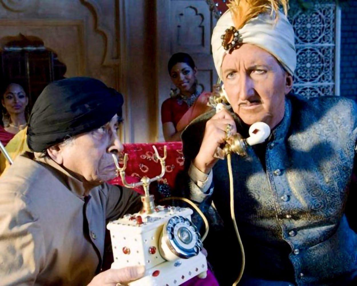 Zwei Männer in Turbans. Einer telefoniert mit einem alten Telefon, der andere schaut zu.