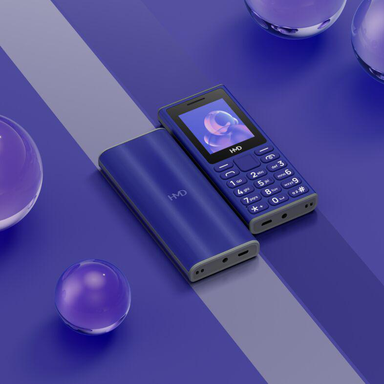 Zwei blaue HMD-Telefone mit Ladeanschluss auf einer blauen Oberfläche mit schwebenden lila Kugeln.