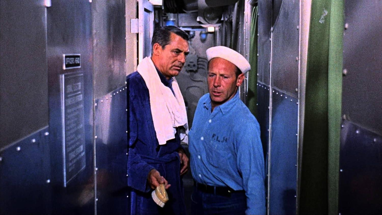 Zwei Männer in einem U-Boot, einer im Bademantel, der andere in Matrosenuniform, unterhalten sich.