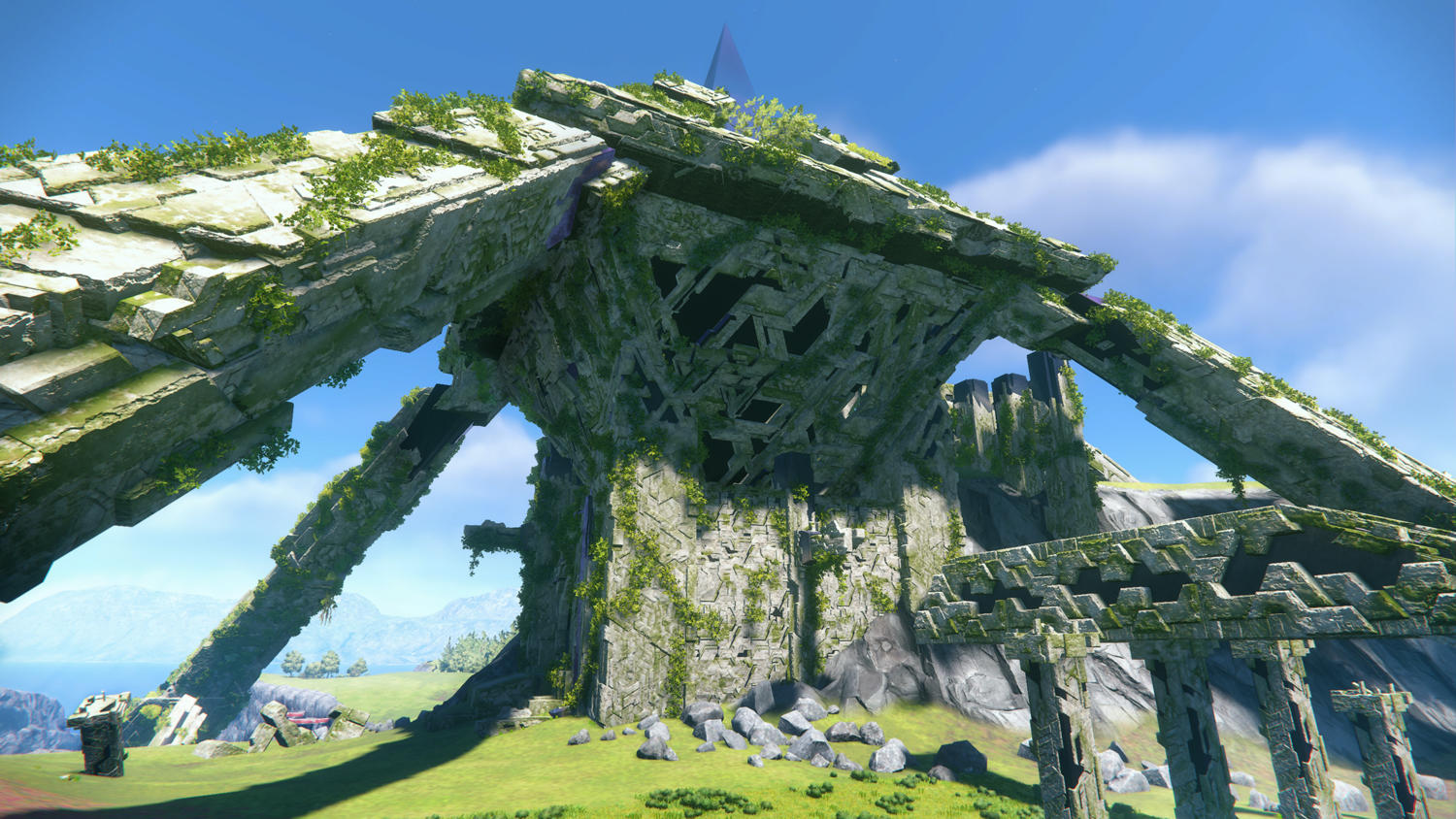 Zerfallene Steinstruktur mit Bögen, mit Moos bedeckt, mit blauem Himmel und See im Hintergrund.