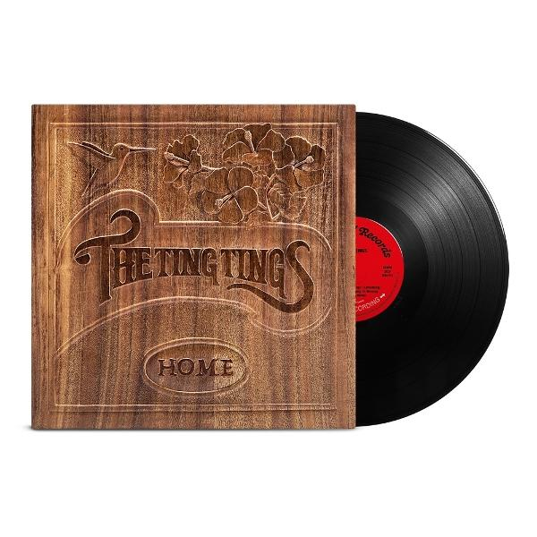 Albumcover mit holzartigem Hintergrund und einer Vinyl-Schallplatte. Text: The Ting Tings, Home.