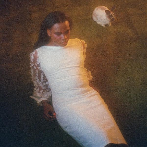 Eine Frau in einem weißen Kleid liegt auf dem Boden. Ein Schädel schwebt über ihr.
