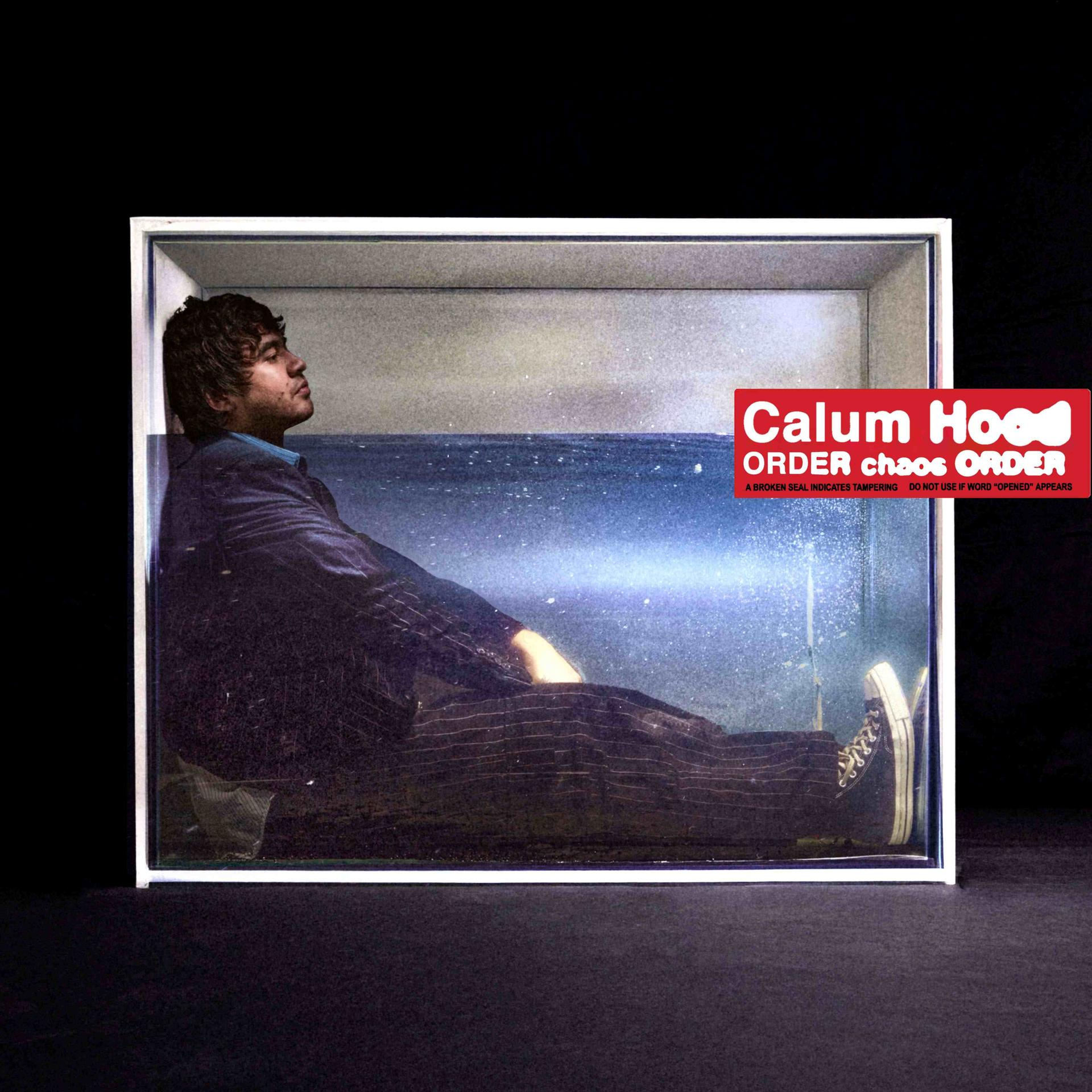 Albumcover: Mann im Anzug in einem Wassertank, ein Label mit Titel und Text.