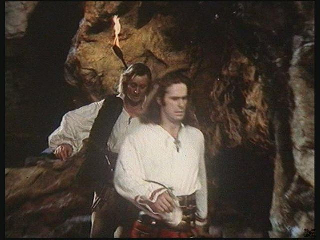Zwei Männer in einer Höhle, einer hält eine Fackel und schaut den anderen an.