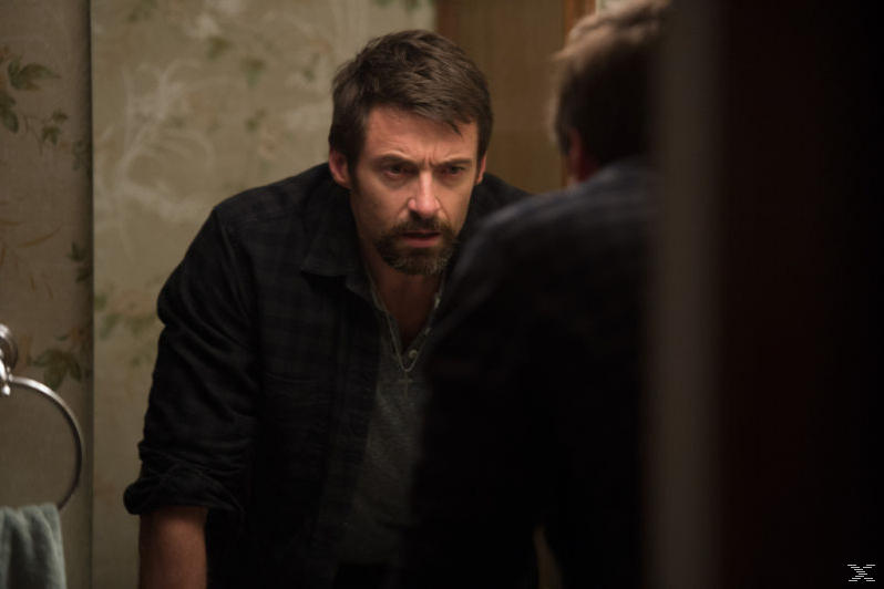 Hugh Jackman betrachtet seine Spiegelung in einem Spiegel. Badezimmer-Umgebung.