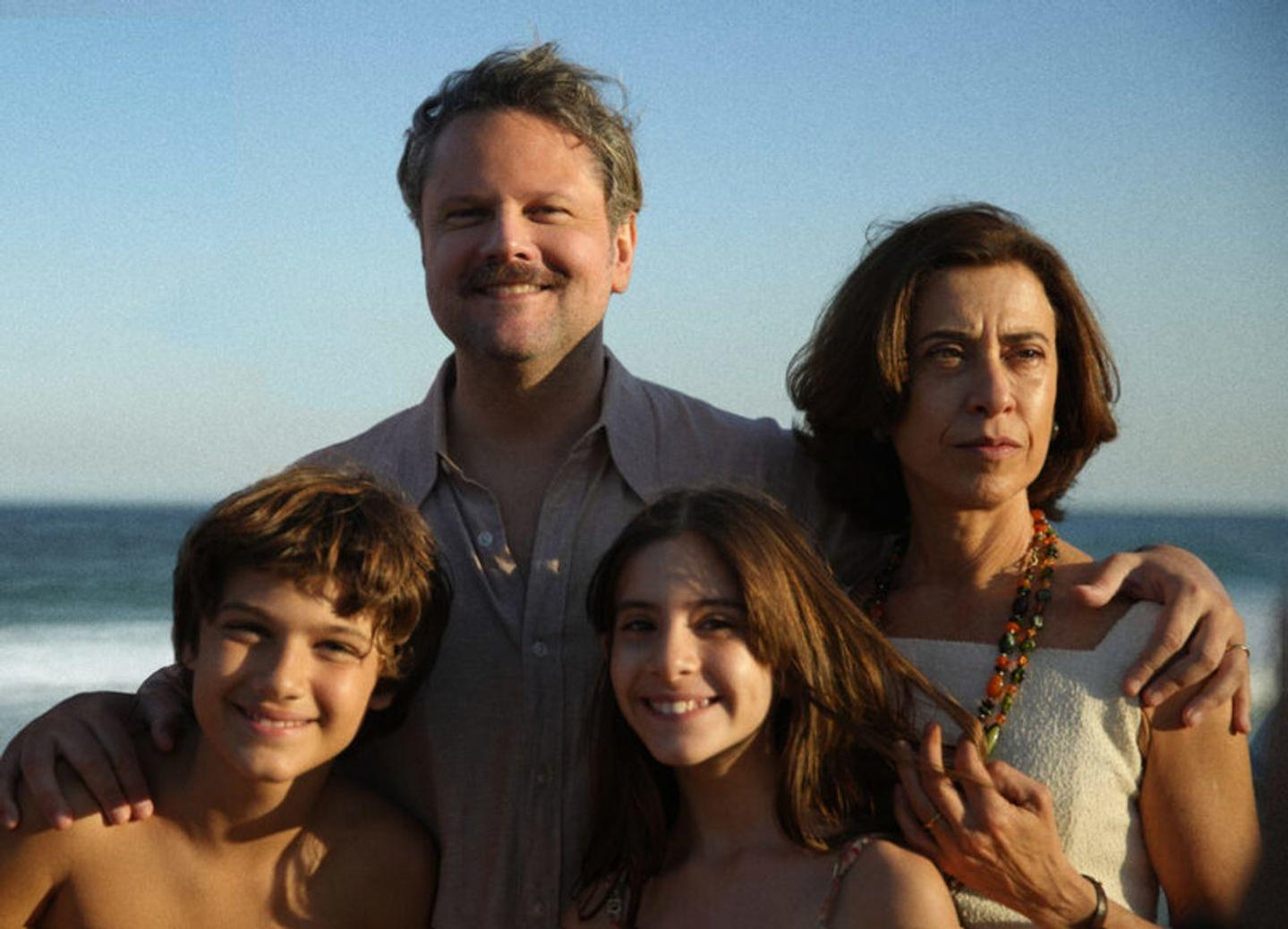 Eine vierköpfige Familie steht zusammen an einem Strand. Sie lächeln in die Kamera.