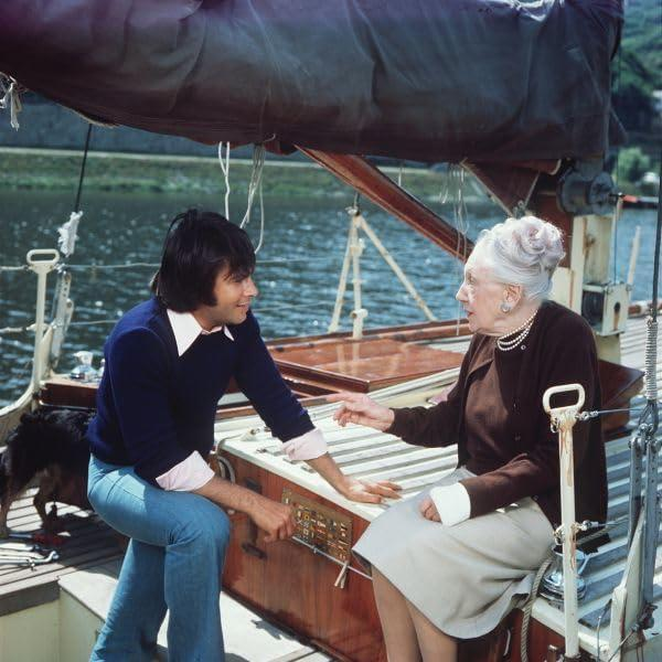 Ein Mann und eine Frau auf einem Boot unterhalten sich; ein Hund ist in der Nähe.