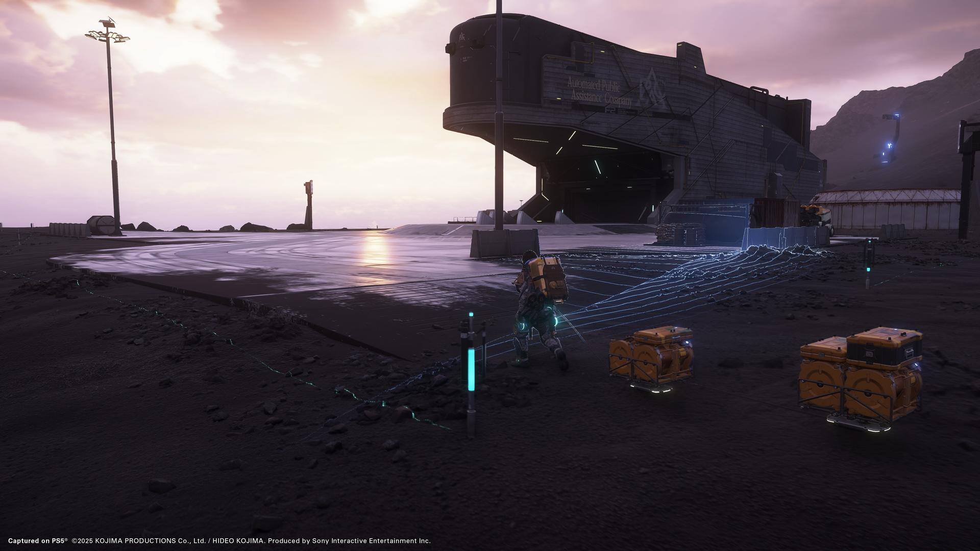 Eine Figur geht auf eine große Struktur mit orangefarbenen Kisten zu. Der Himmel ist bedeckt.