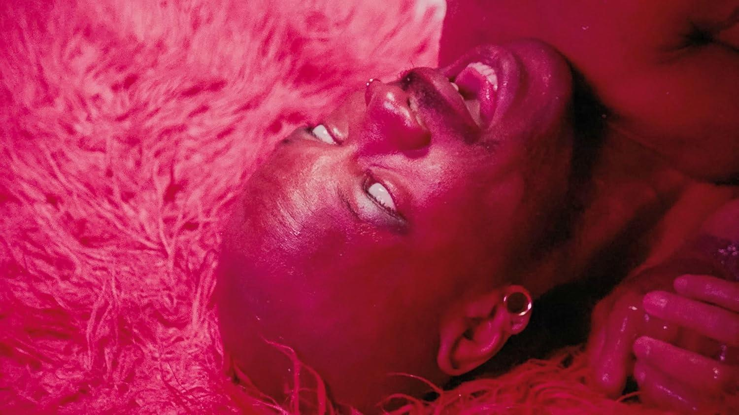 Nahaufnahme eines Gesichts, Augen geschlossen, mit pinkfarbenem, flauschigem Hintergrund.