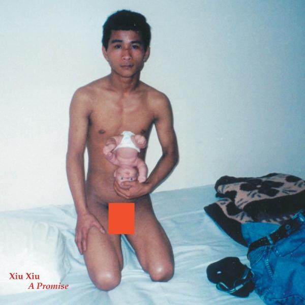Mann hält ein Baby. Text: Xiu Xiu A Promise. Zensierter Bereich.