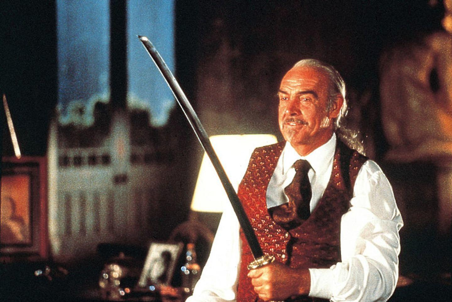 Sean Connery hält ein Katana. Er trägt eine Weste und steht in einem Innenraum.