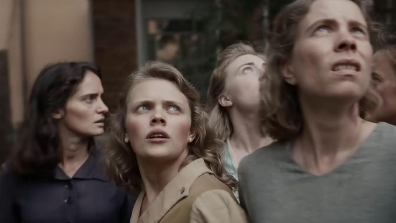 Gruppe von Frauen, die nach oben schauen, mit überraschten Ausdrücken.