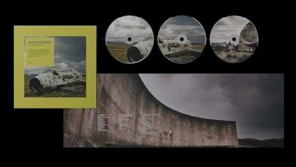 Albumcover mit CD-Discs, gelbem Case und Betonstruktur mit Text auf schwarzem Hintergrund.