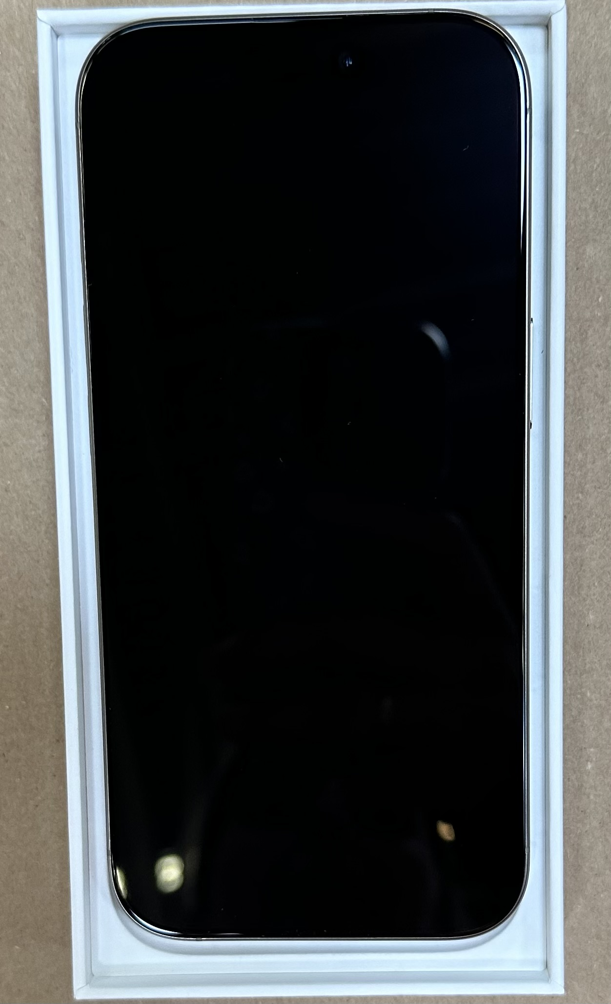 Czarny smartfon w białym pudełku. Telefon wyłączony, ekran czarny.