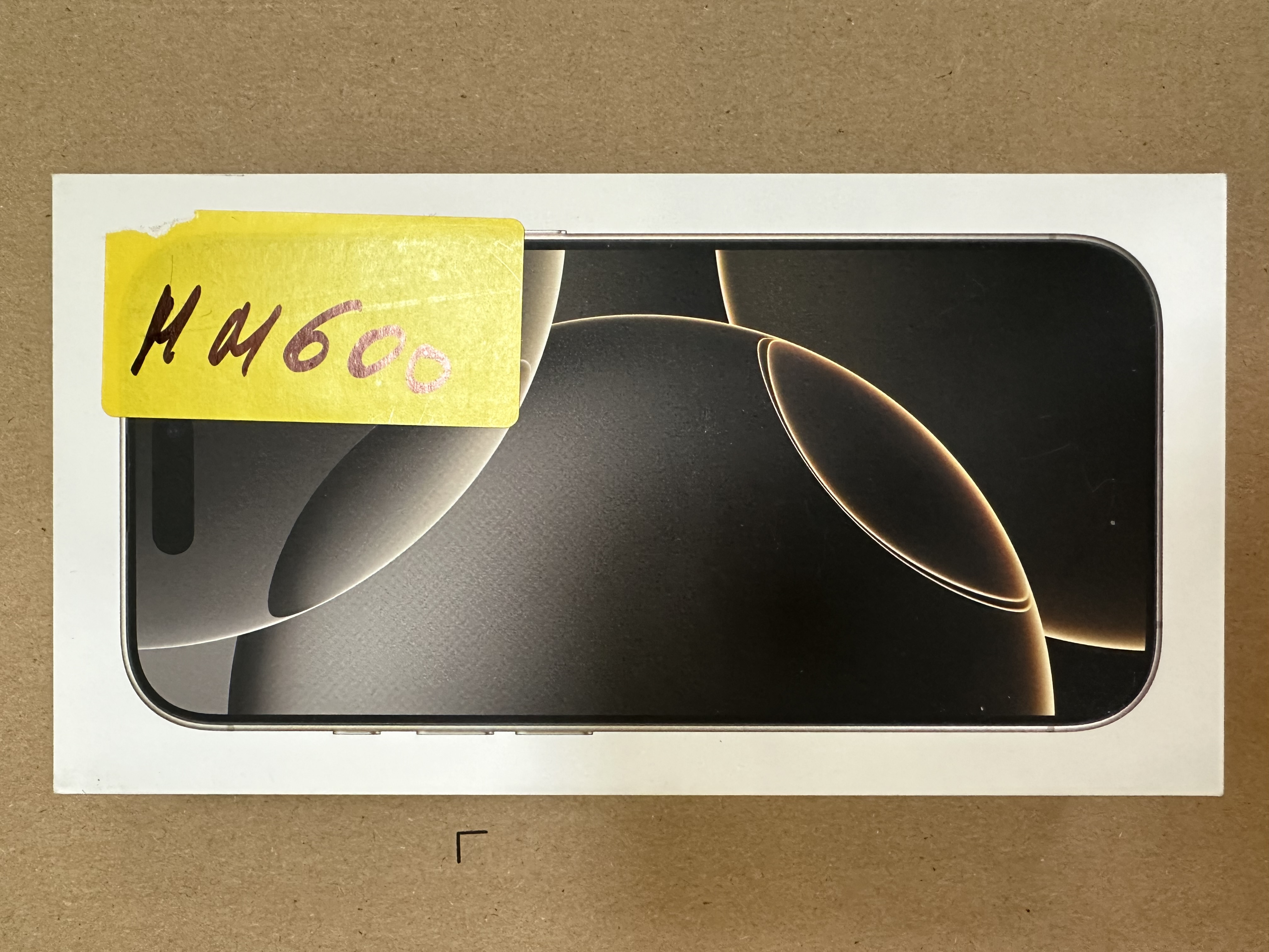 Pudełko smartfona z ciemnym obrazem na ekranie, dołączona żółta naklejka.