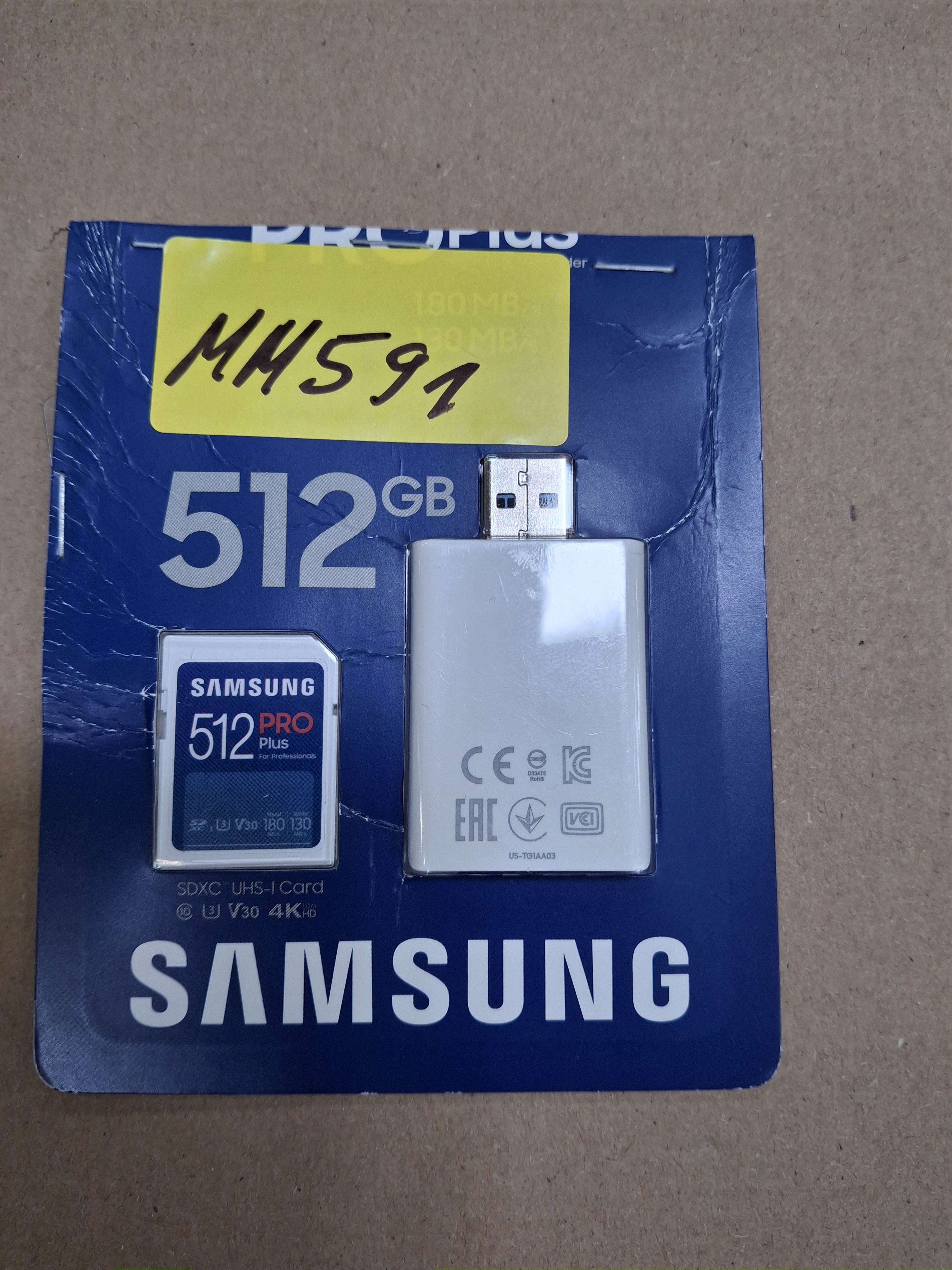 Karta SD Samsung 512 GB i adapter USB znajdują się na niebieskiej karcie. Przyklejona jest żółta naklejka.