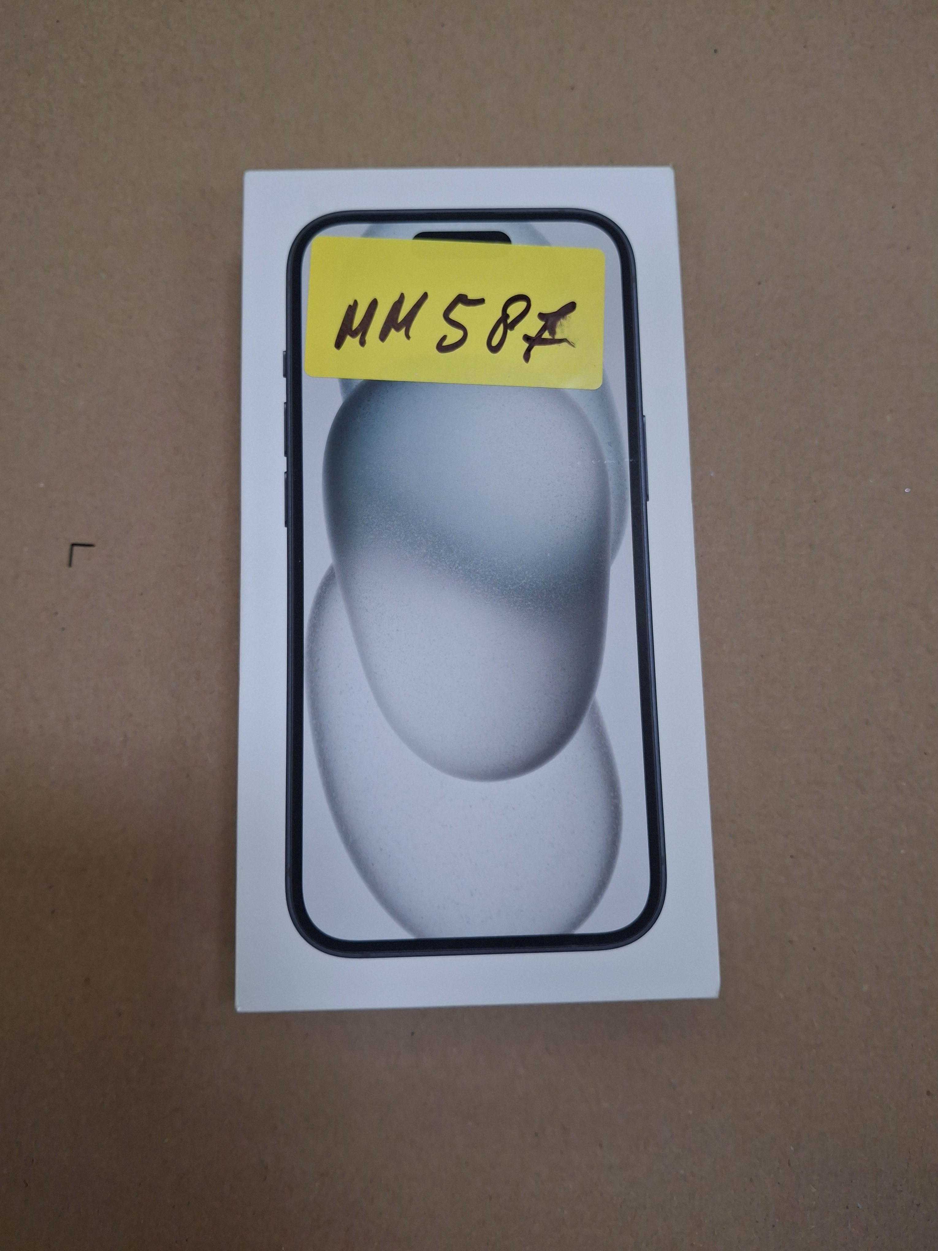 Białe pudełko ze zdjęciem iPhone'a. Na górze pudełka znajduje się żółta naklejka.