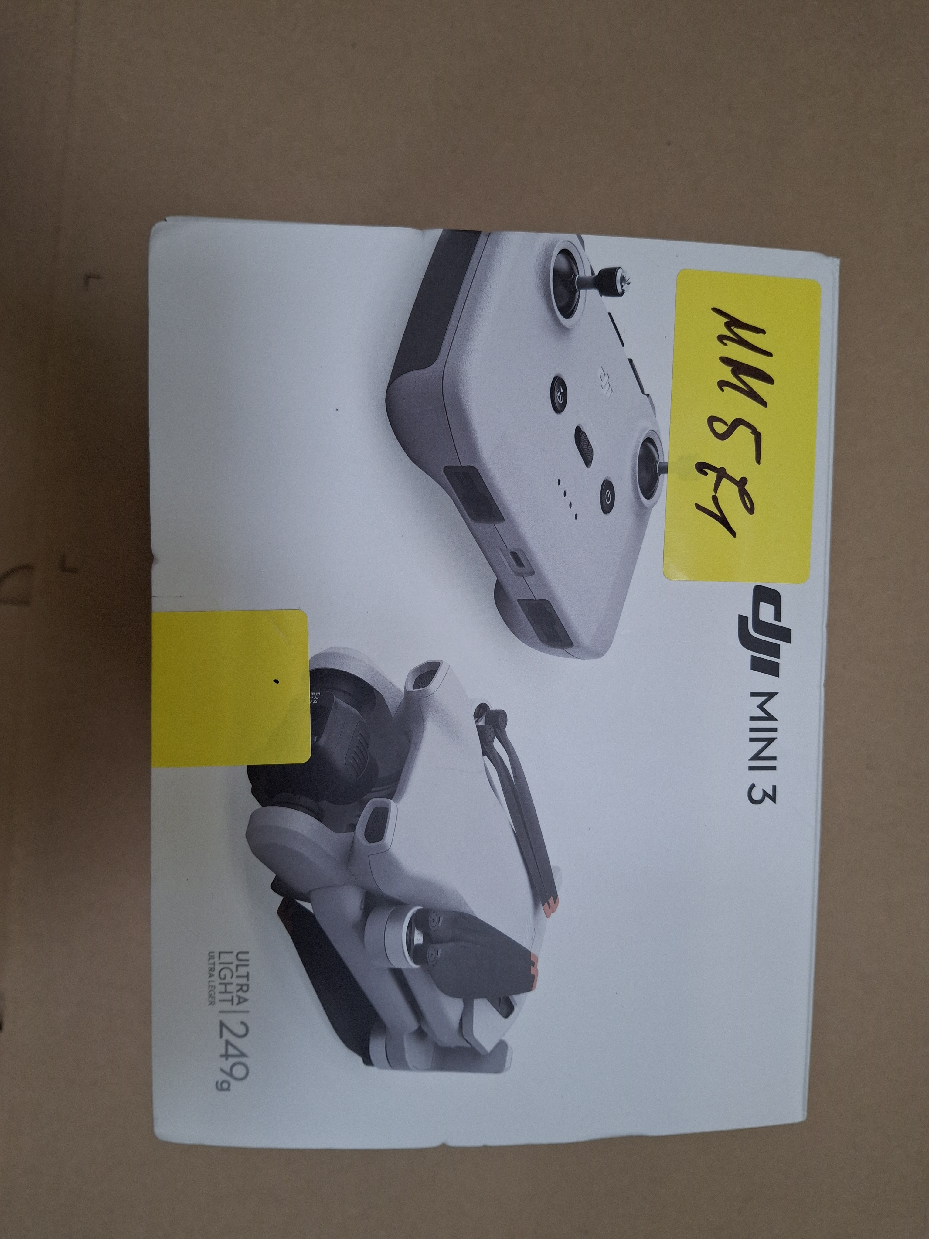 Pudełko drona DJI Mini 3 z pilotem, oznaczone żółtą naklejką.