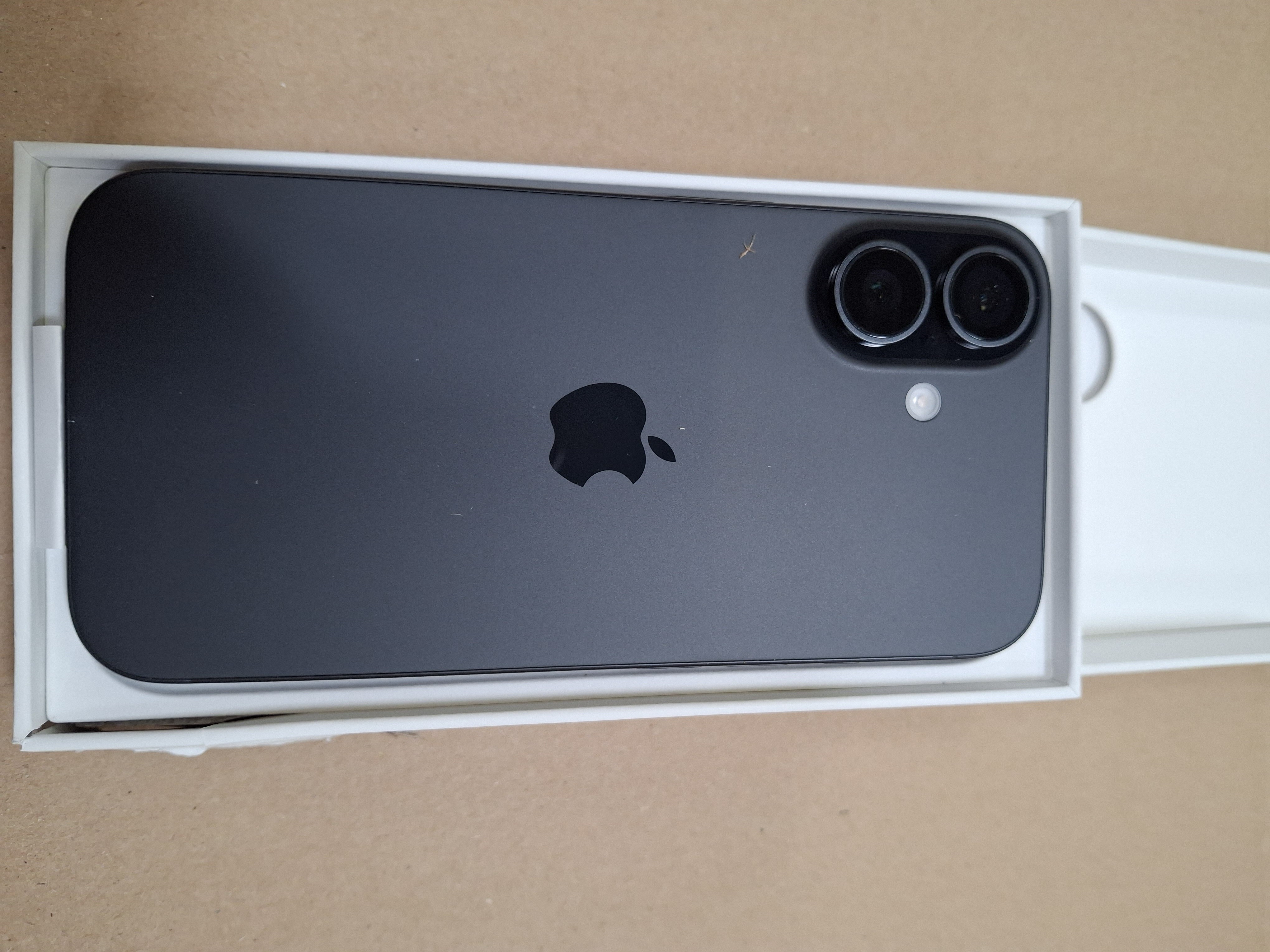Czarny telefon w białym pudełku. Z tyłu widnieje logo Apple i aparaty.