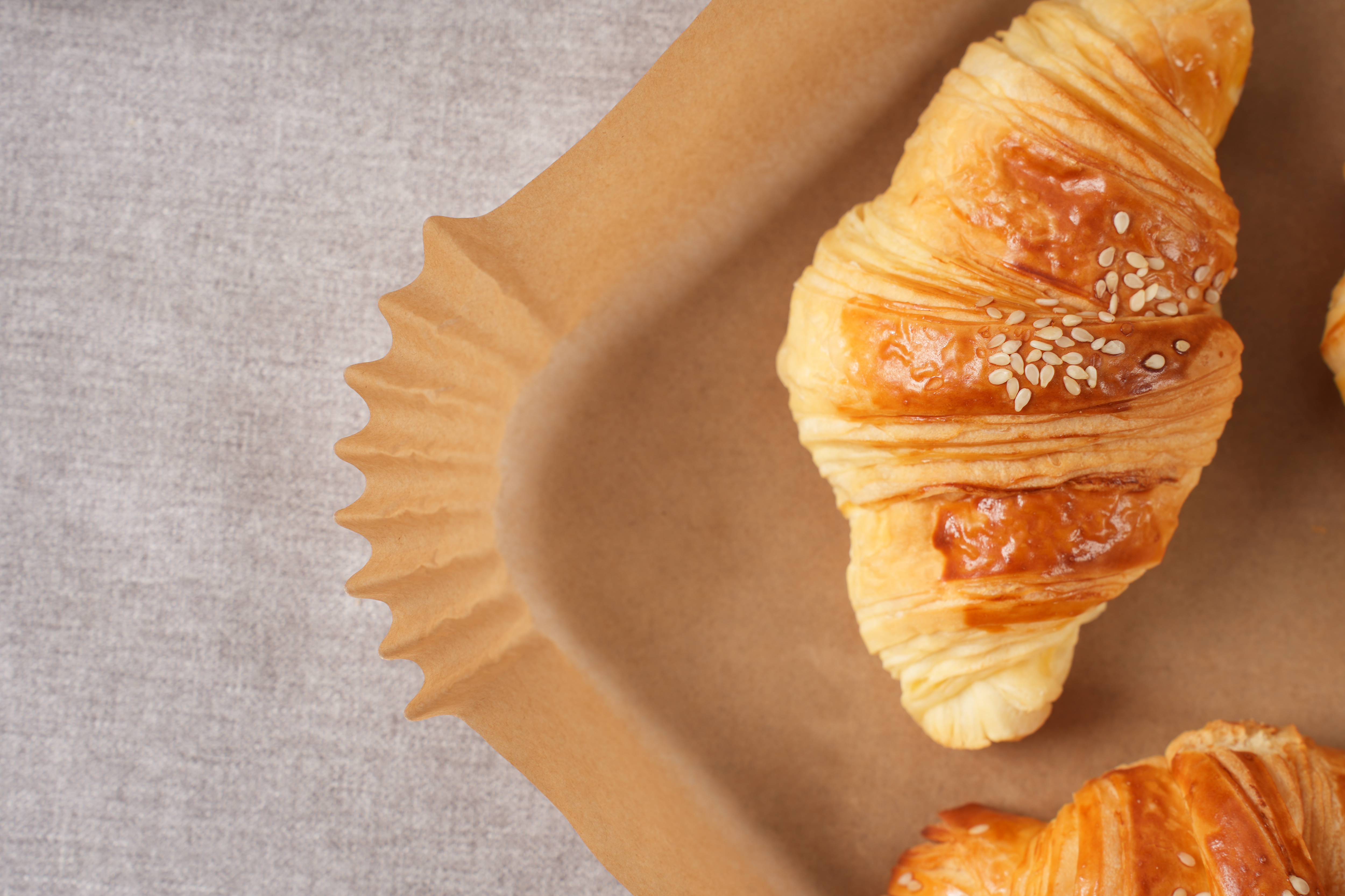 Rogaliki na brązowej papierowej tacy, z jasnoszarym tłem z tkaniny.