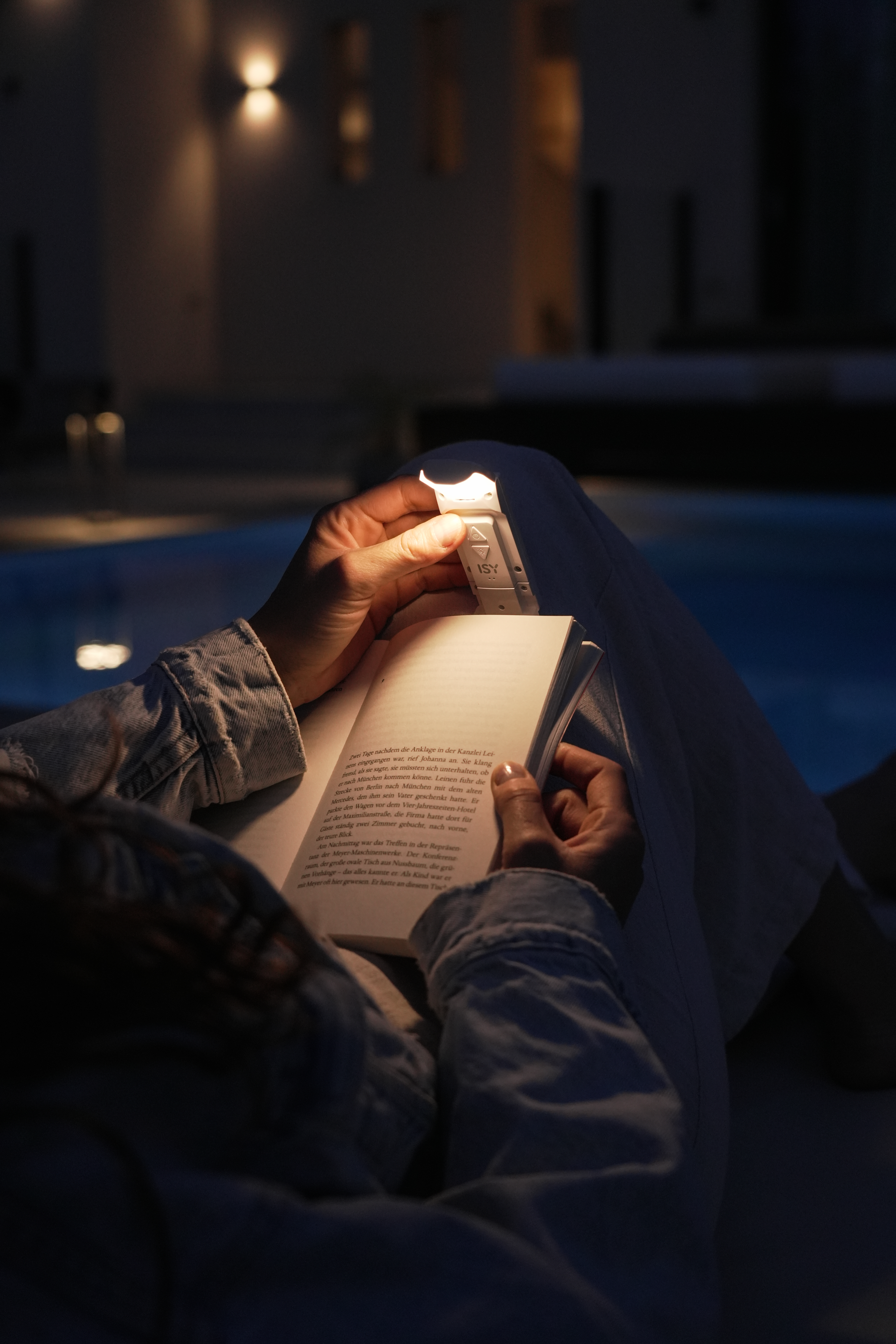 Une personne lisant un livre avec une lampe de lecture.