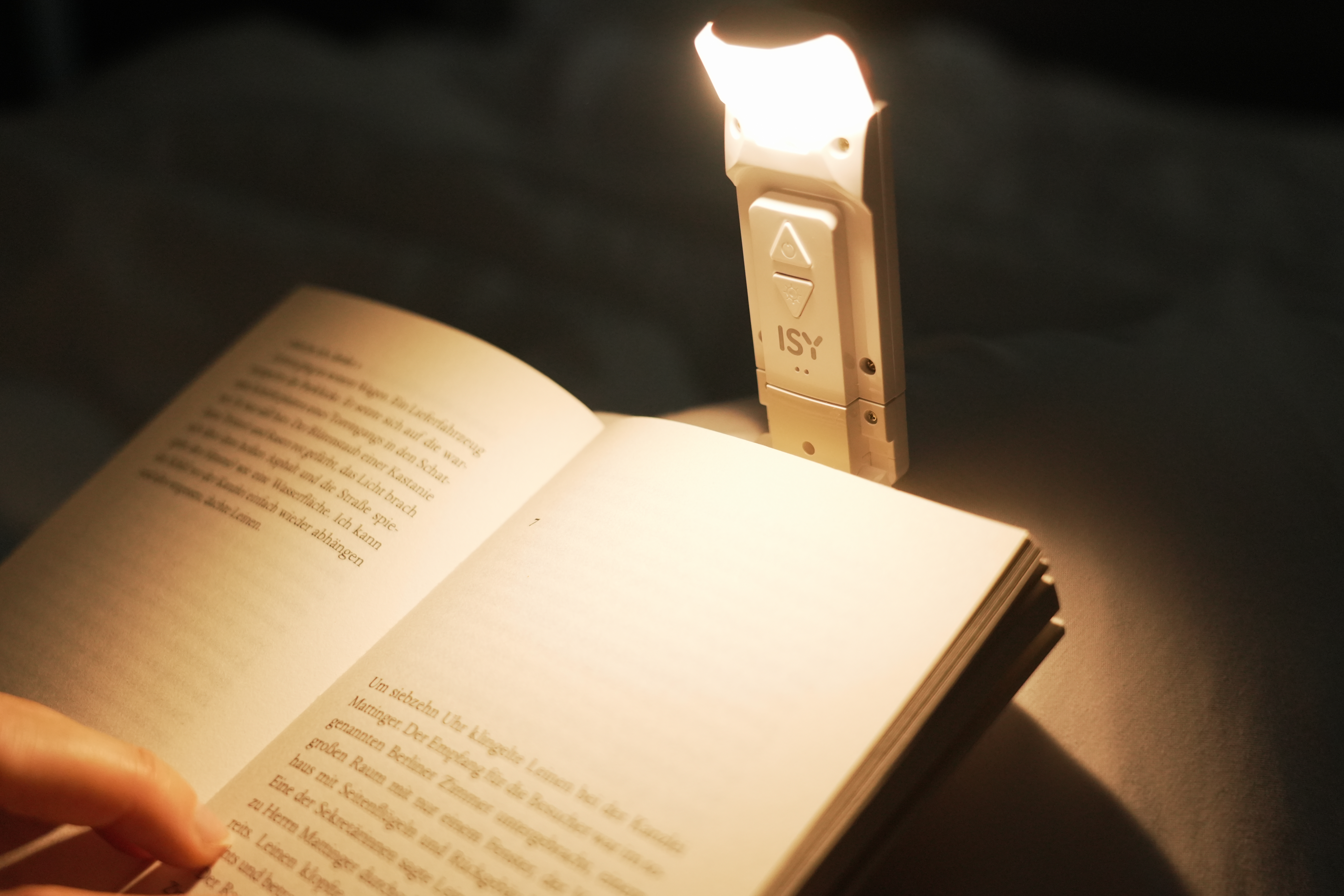 Un livre avec une lampe de lecture attachée, illuminant les pages ouvertes.