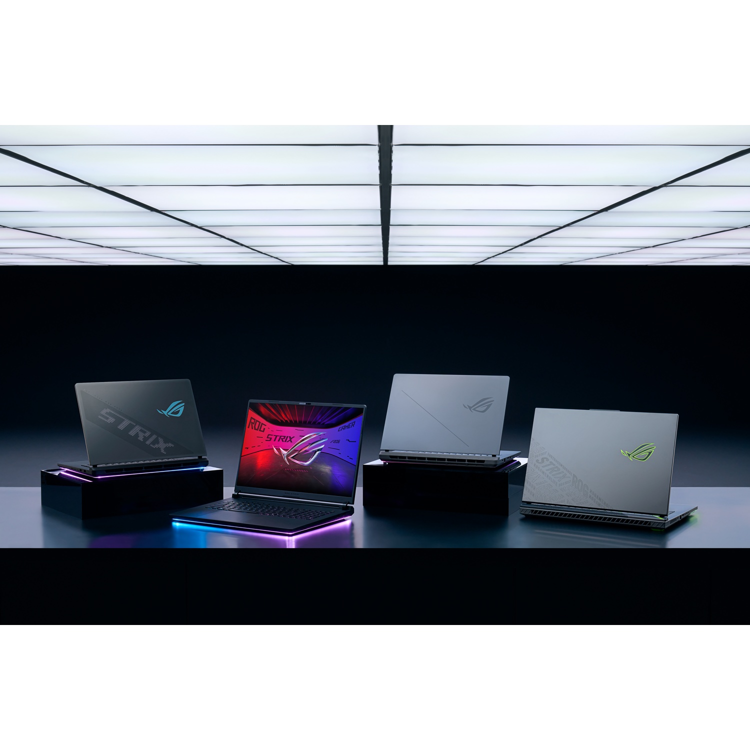 Quattro laptop ROG Strix esposti su supporti con sfondo illuminato.