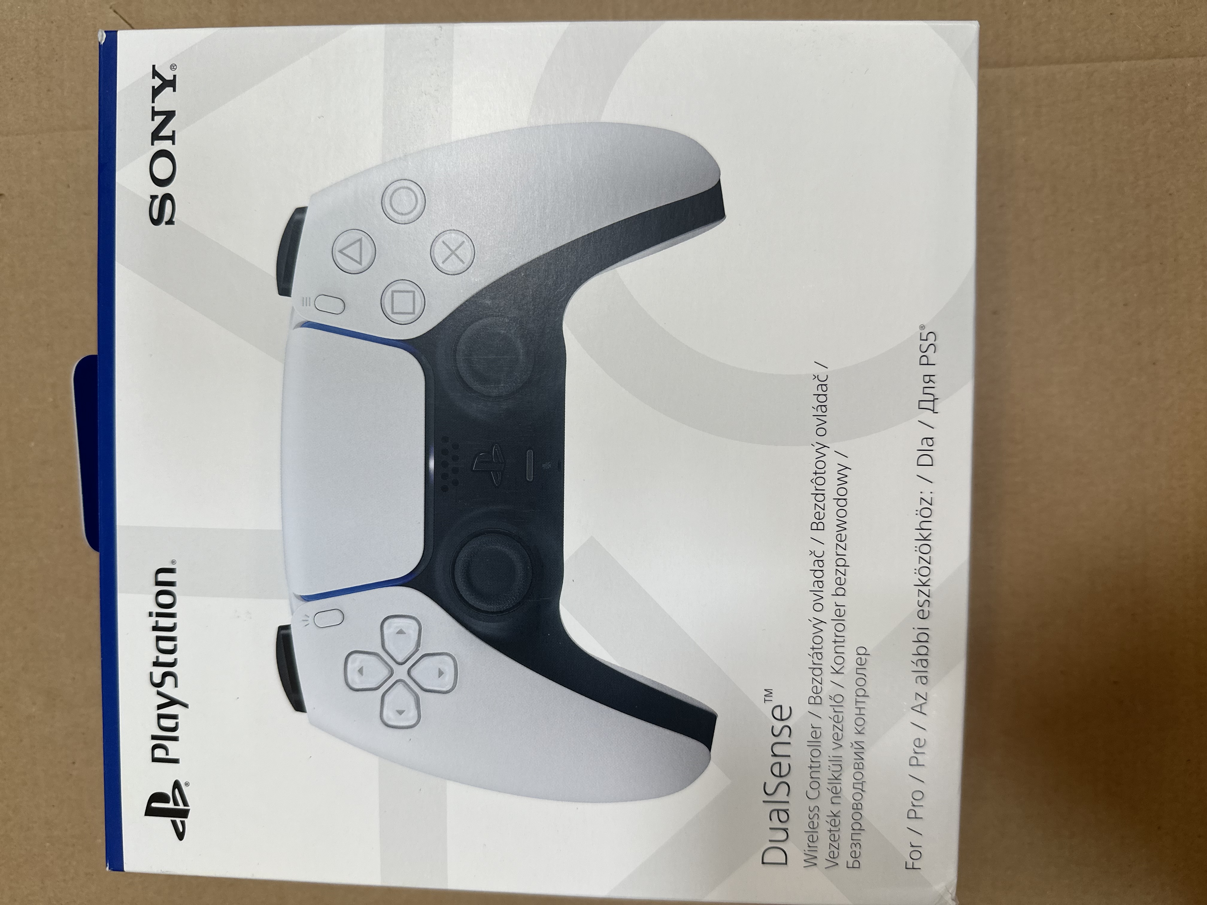 Kontroler Playstation Dualsense w pudełku, widok z góry. Schemat kolorów biały i czarny.