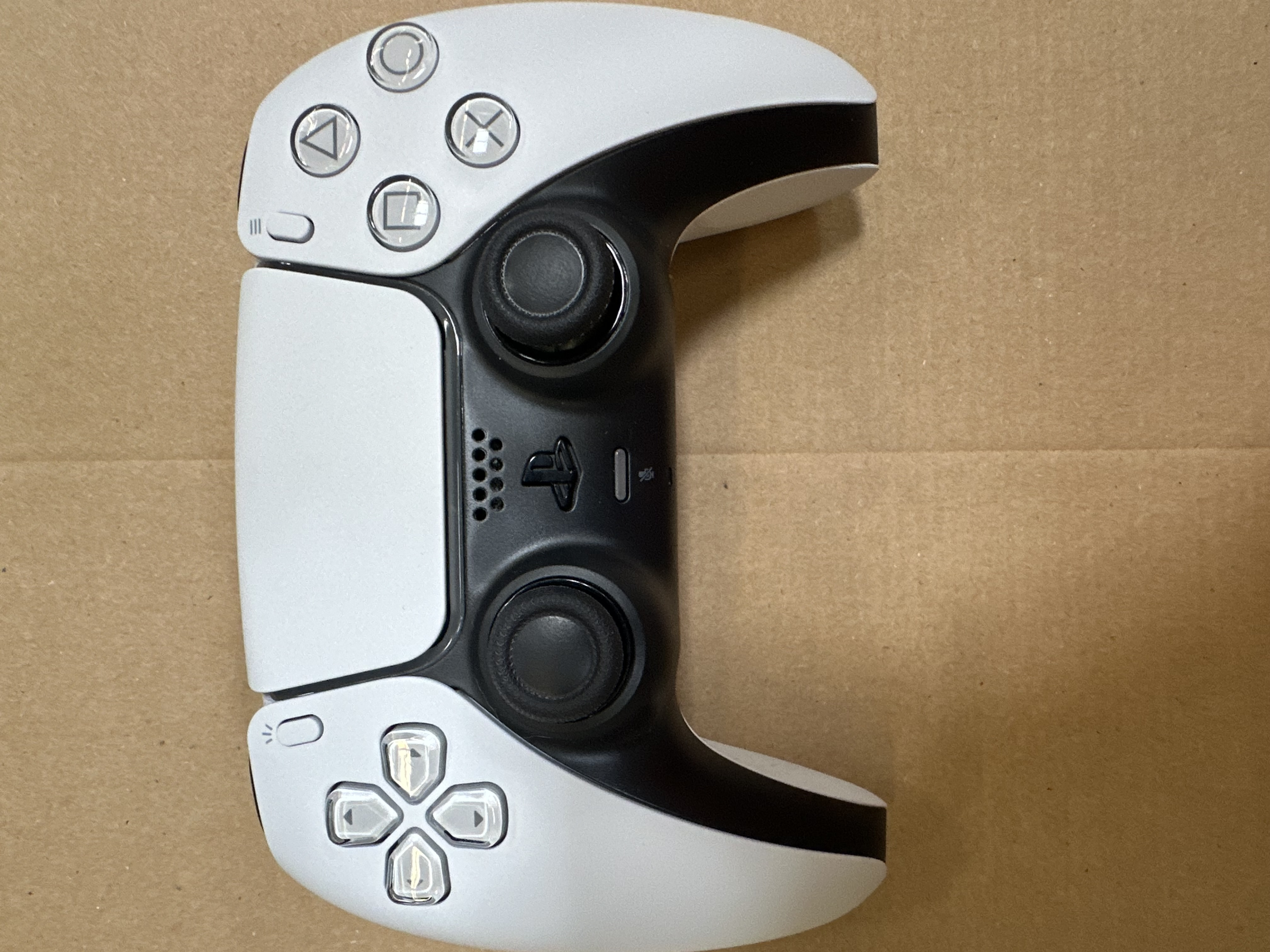 Kontroler Playstation Dualsense, widok z góry. Schemat kolorów biały i czarny.