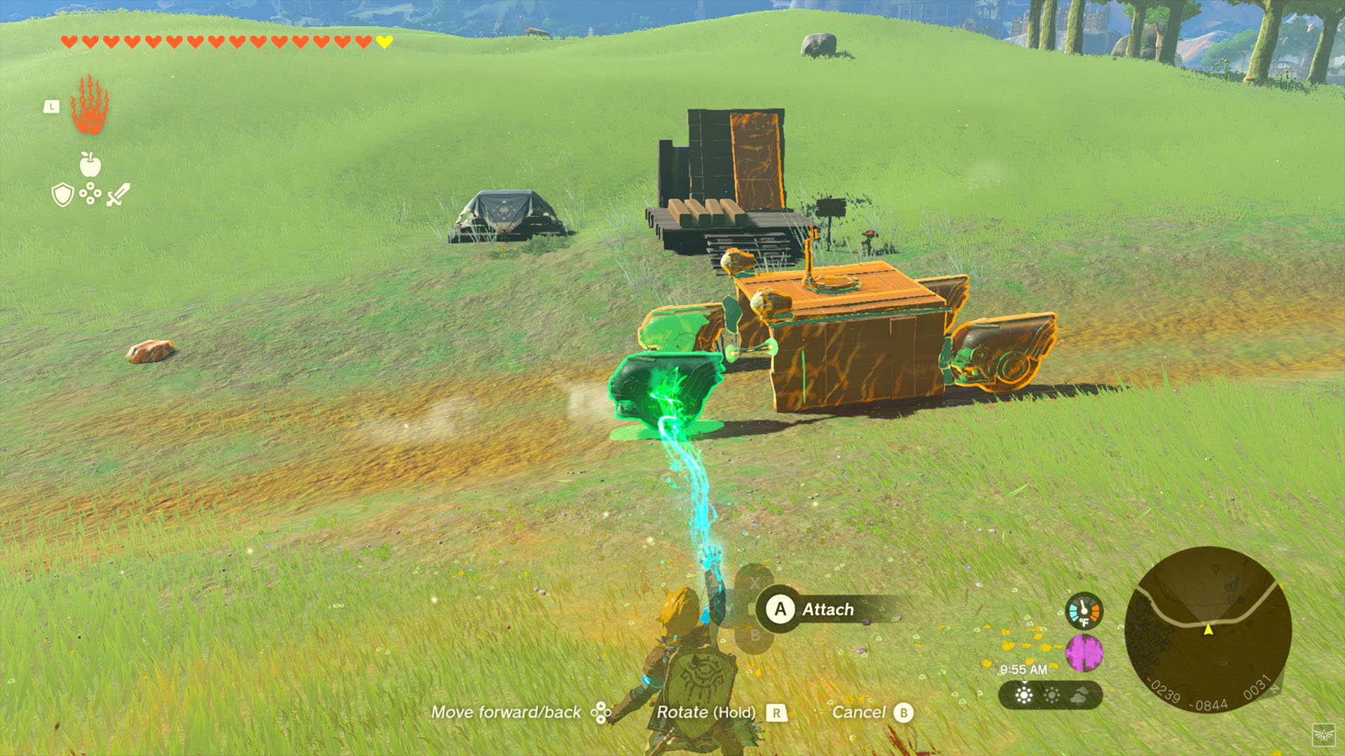 Bir karakter, çimenli bir tarlada yeşil bir nesneyi mavi bir enerji ışınıyla bir arabaya takıyor.