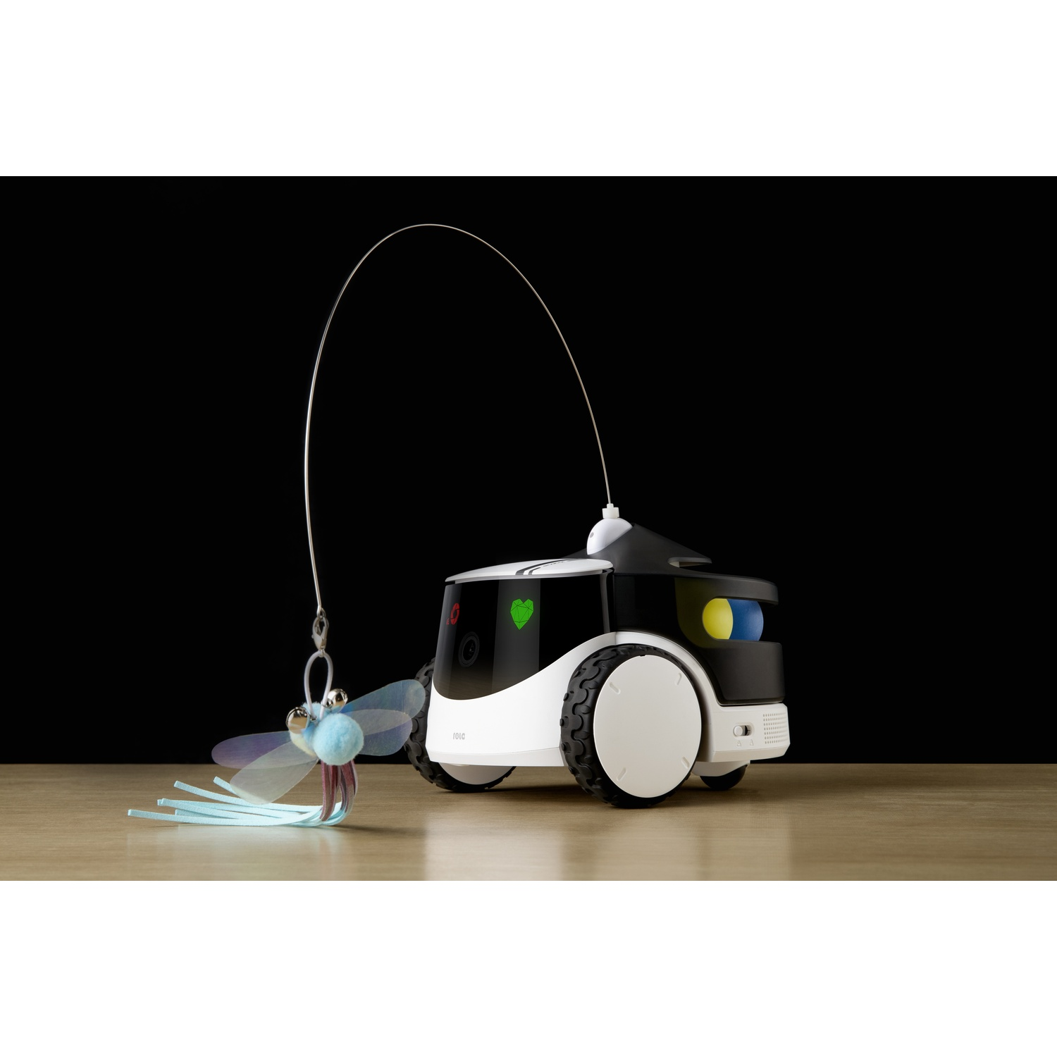 Un giocattolo robot per animali con un giocattolo a forma di libellula. Sfondo nero, superficie in legno.