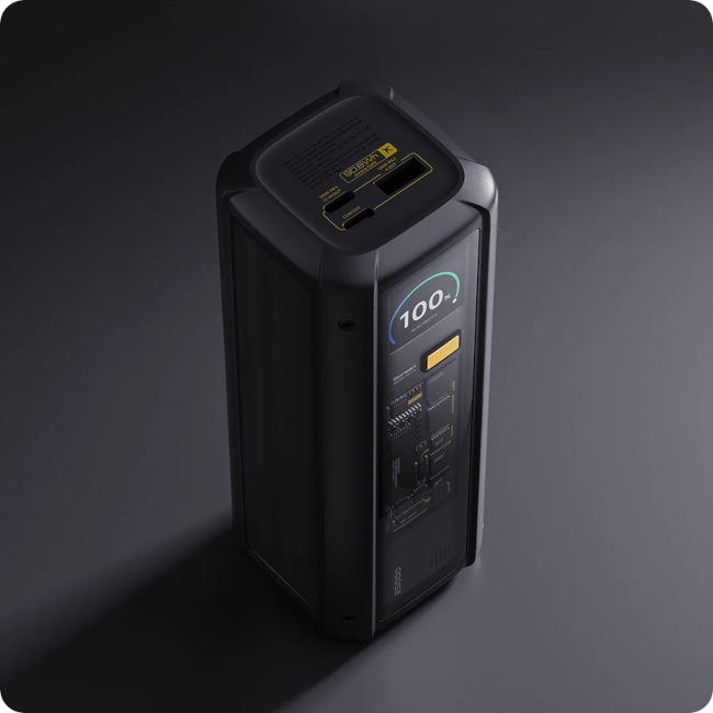 Czarny power bank, widok z góry. Pokazuje ekran ze 100% naładowania i różne porty/przyciski na górze.