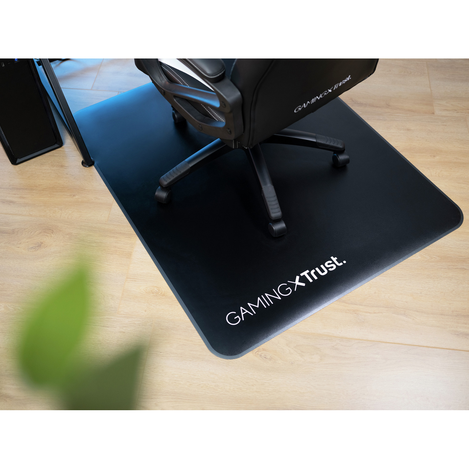 Black gaming chair mat on wood floor. Chair sits on the mat.