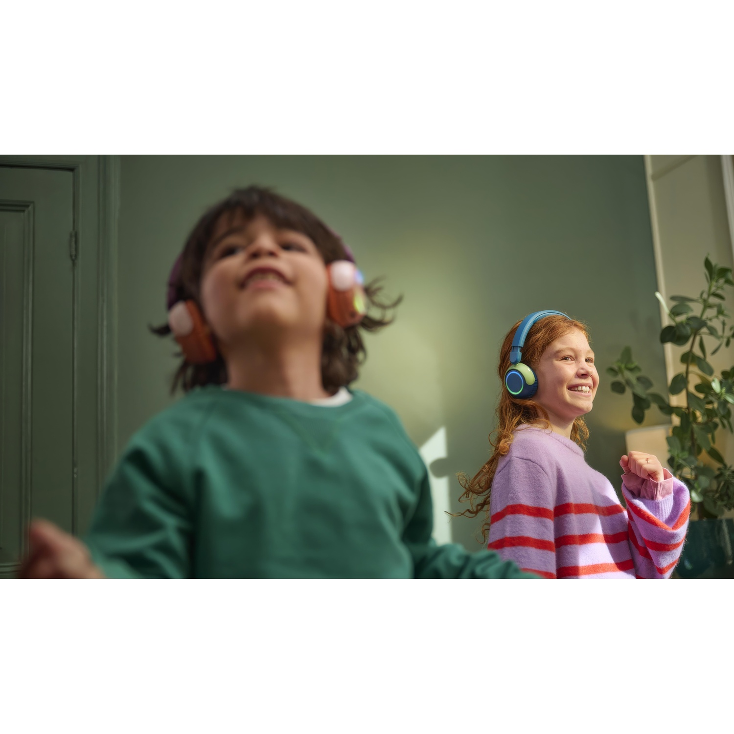 Due bambini con le cuffie sorridono e ballano in una stanza.