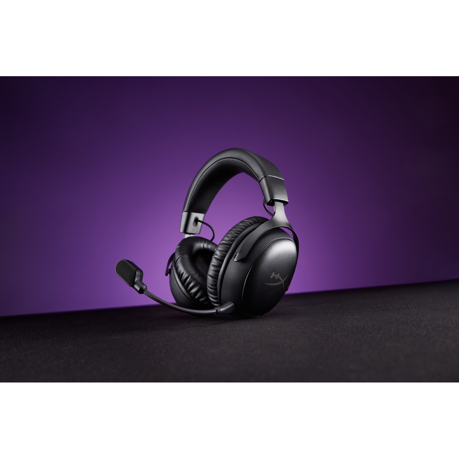 Casque de jeu HyperX noir avec micro, sur une surface noire avec fond violet.