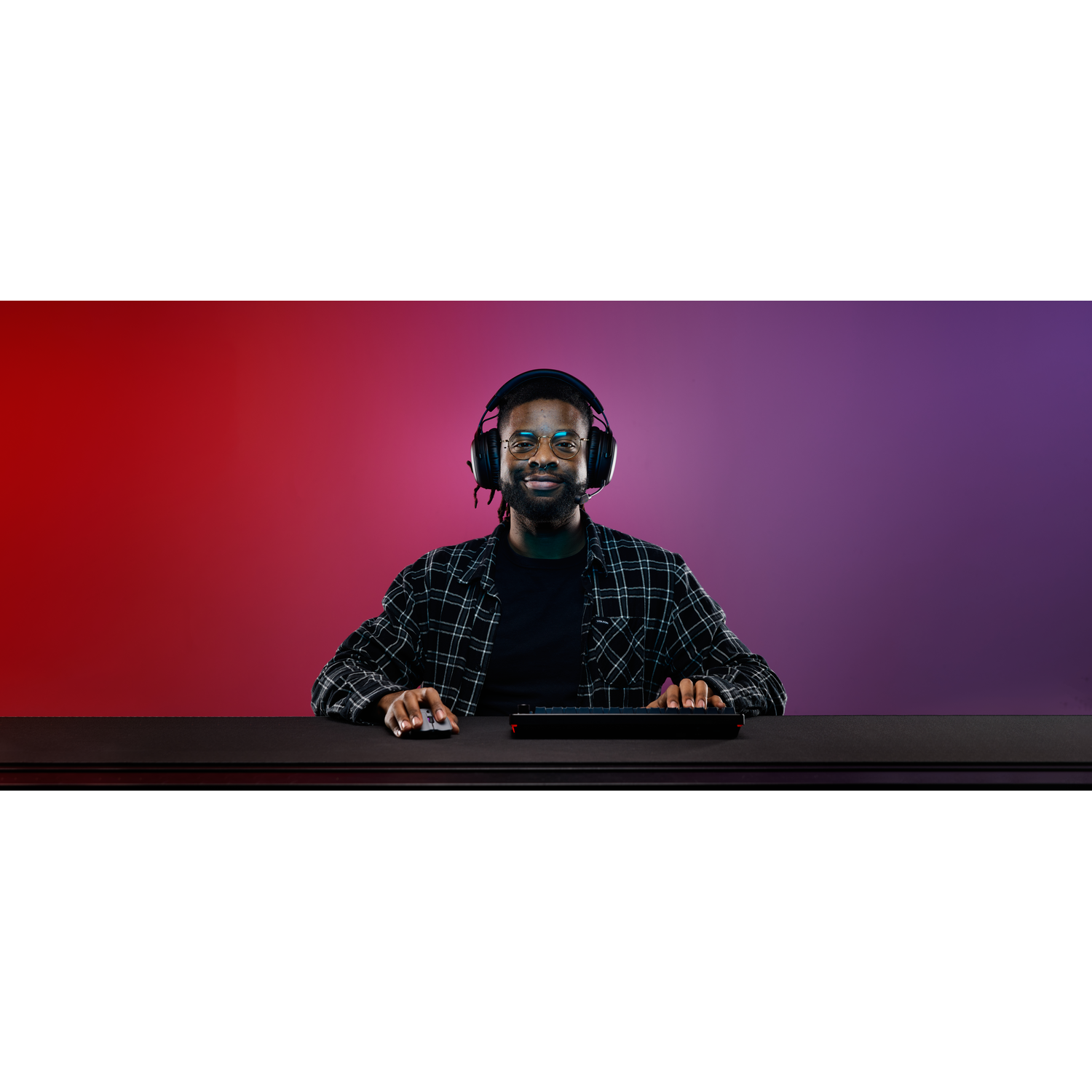 Homme avec casque, lunettes et chemise à carreaux, utilisant clavier et souris.