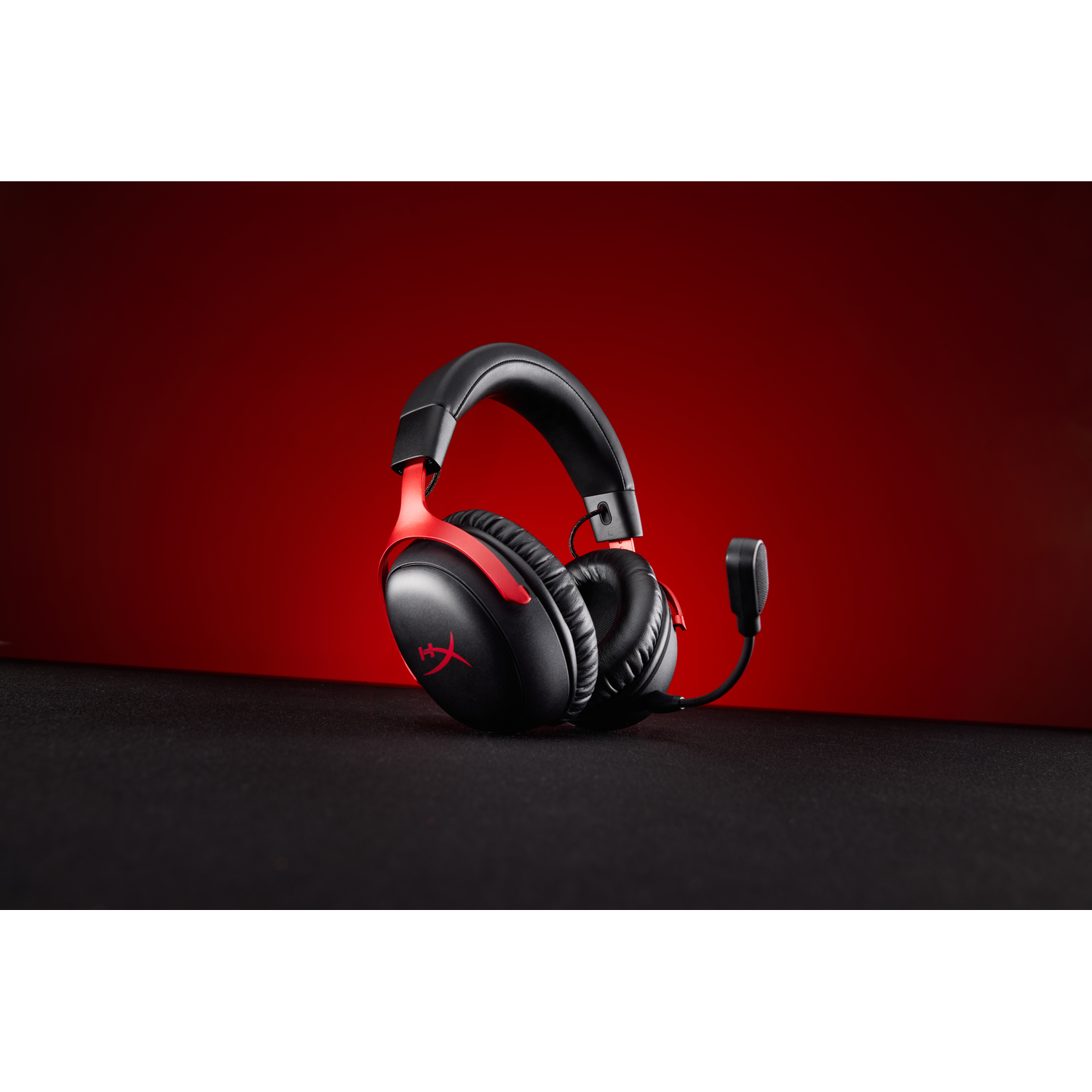 Black and red headphones, with a microphone, on a black surface.