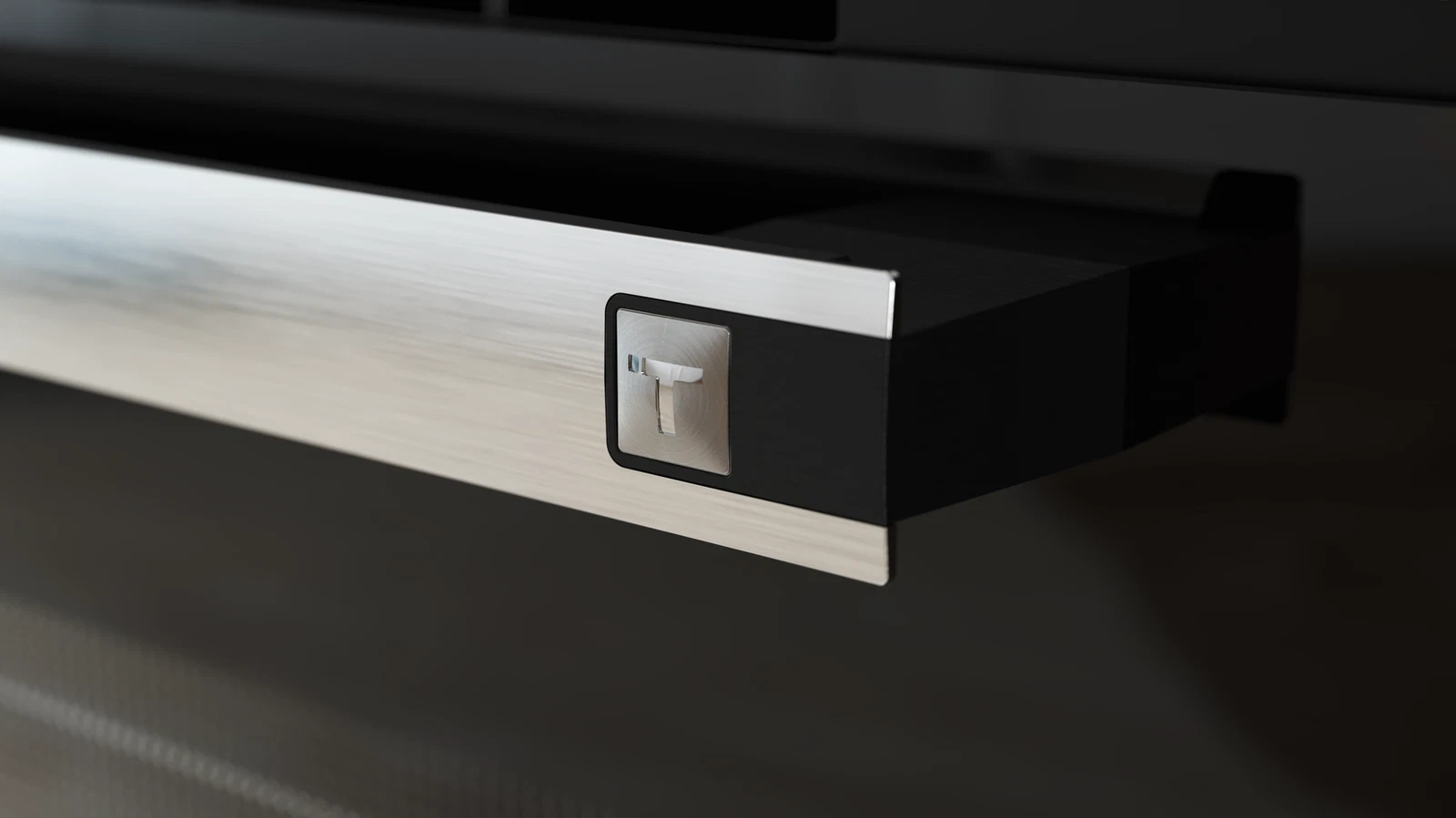 Primer plano de la manija del horno con el logotipo de Teka en gabinetes gris oscuro.