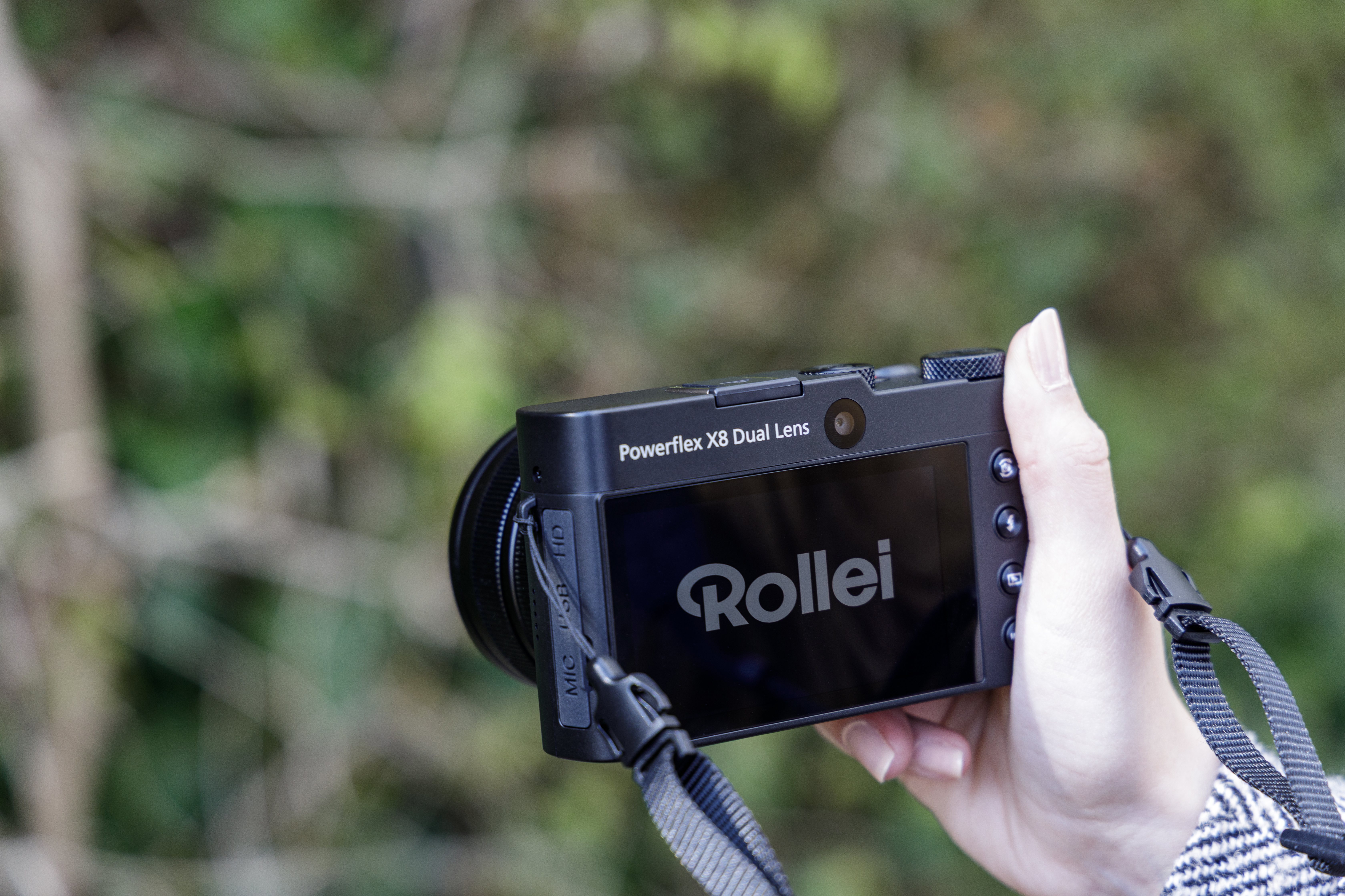 Eine Person hält eine schwarze Kamera und zeigt den Bildschirm und das Rollei-Logo.