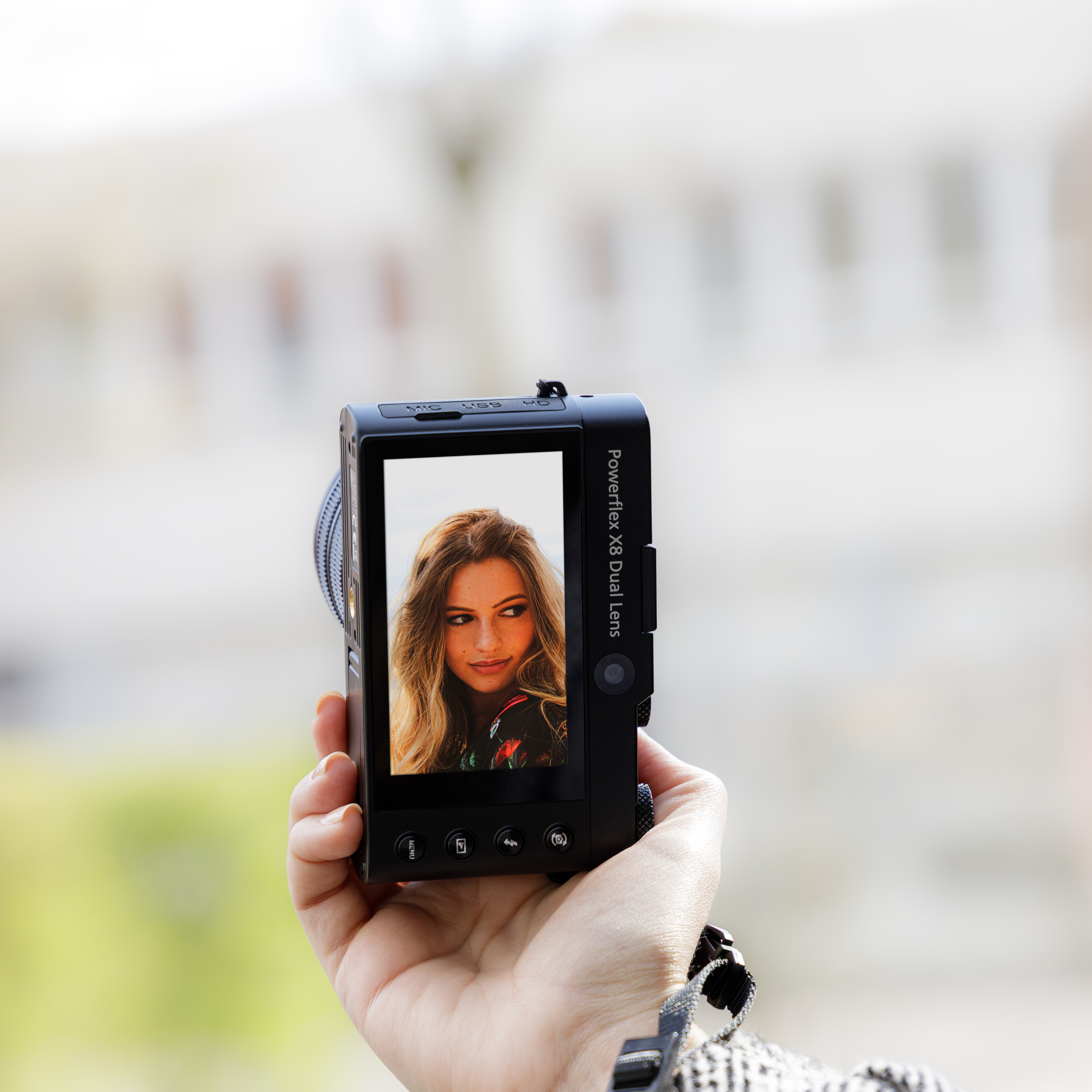 Eine Person hält eine Kamera und zeigt ein Foto einer Frau auf dem Bildschirm.