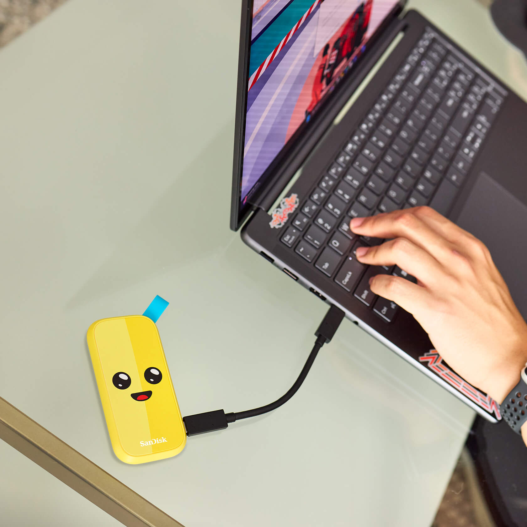 Un'unità USB gialla collegata a un laptop. Mano di una persona vicino alla tastiera.