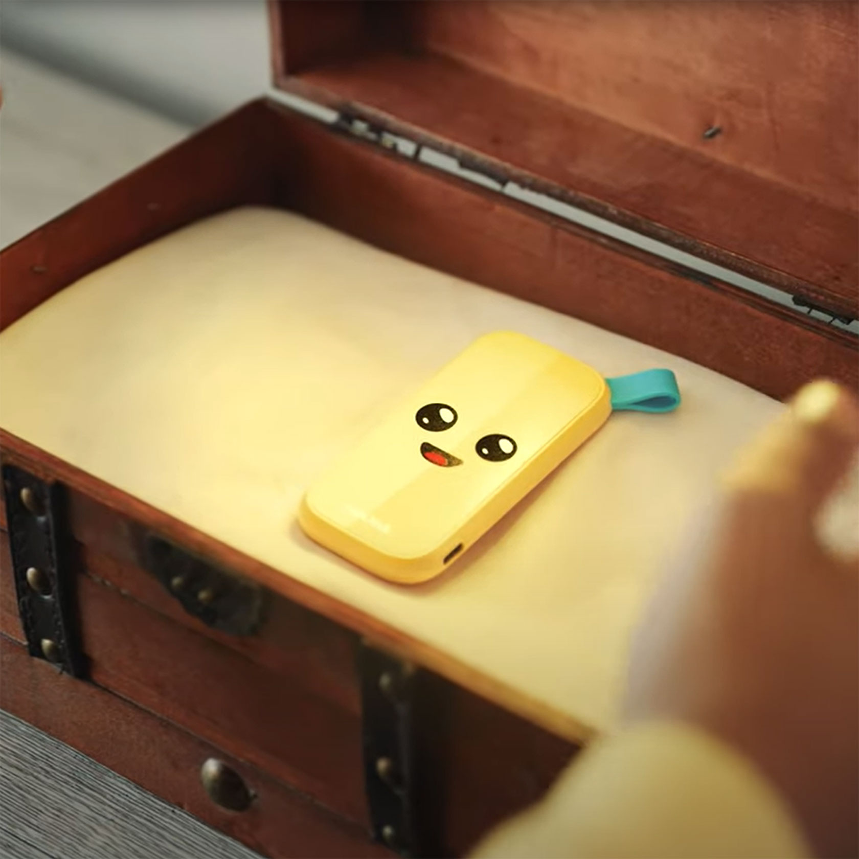 Unità USB gialla con una faccia da cartone animato all'interno di un forziere di legno aperto con un panno bianco.
