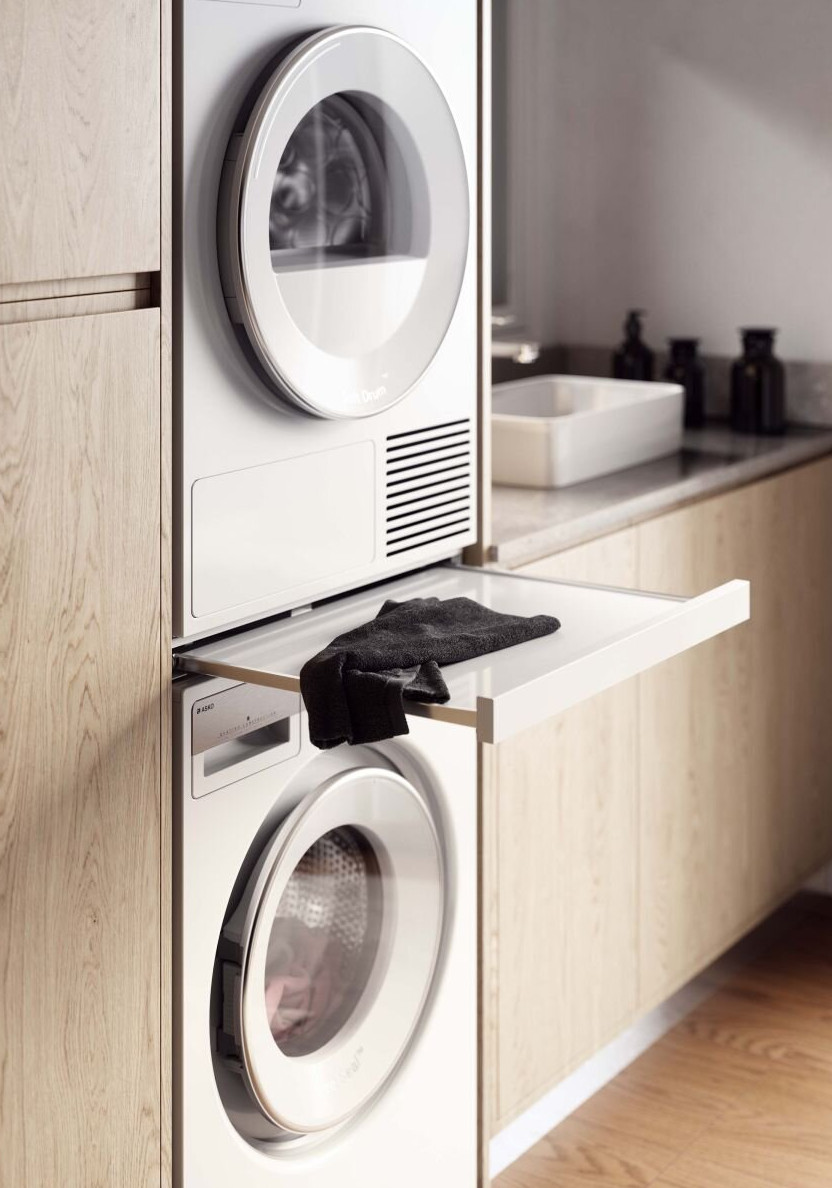 Stos suszarki i pralki z otwartą szufladą, zawierającą czarny ręcznik.