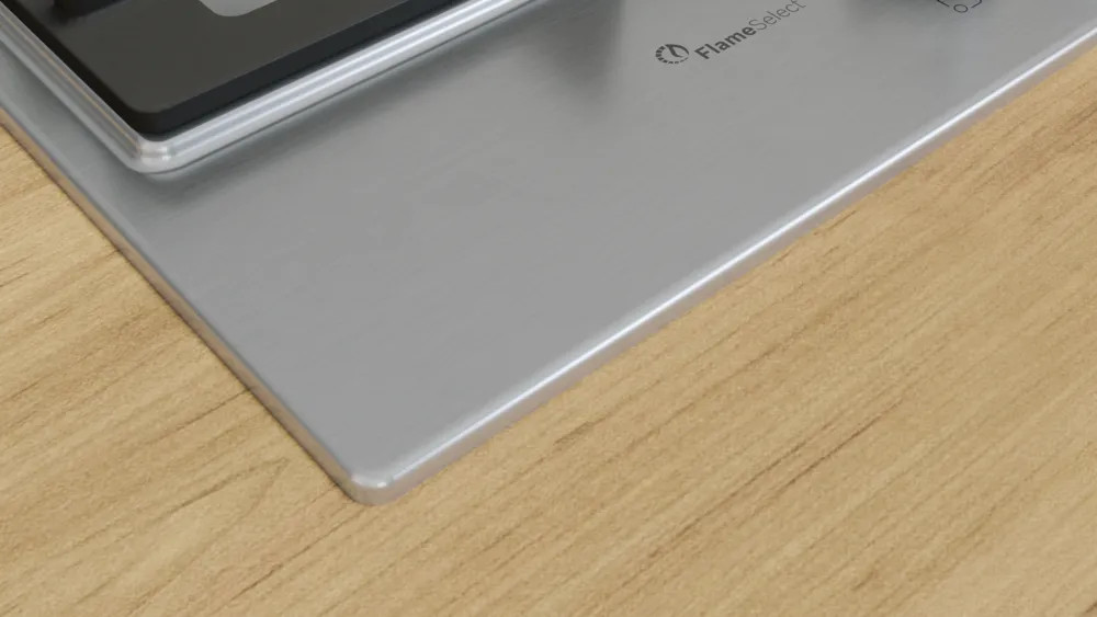 Narożnik gazowej płyty ze stali nierdzewnej. Powierzchnia jest odblaskowa, widoczne drewno.